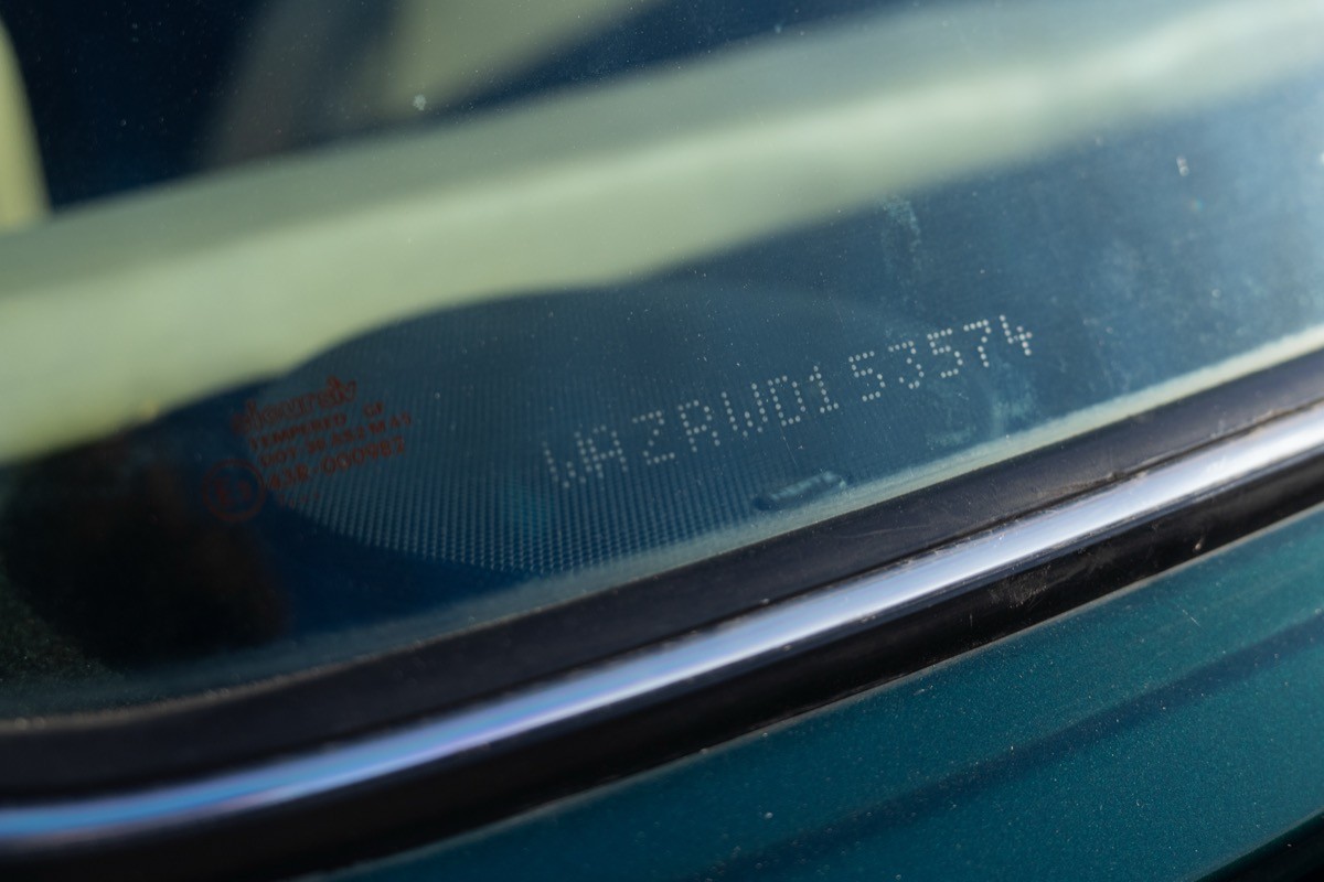 Close-up of a car's window, with a reflection and subtle details visible on the glass surface.