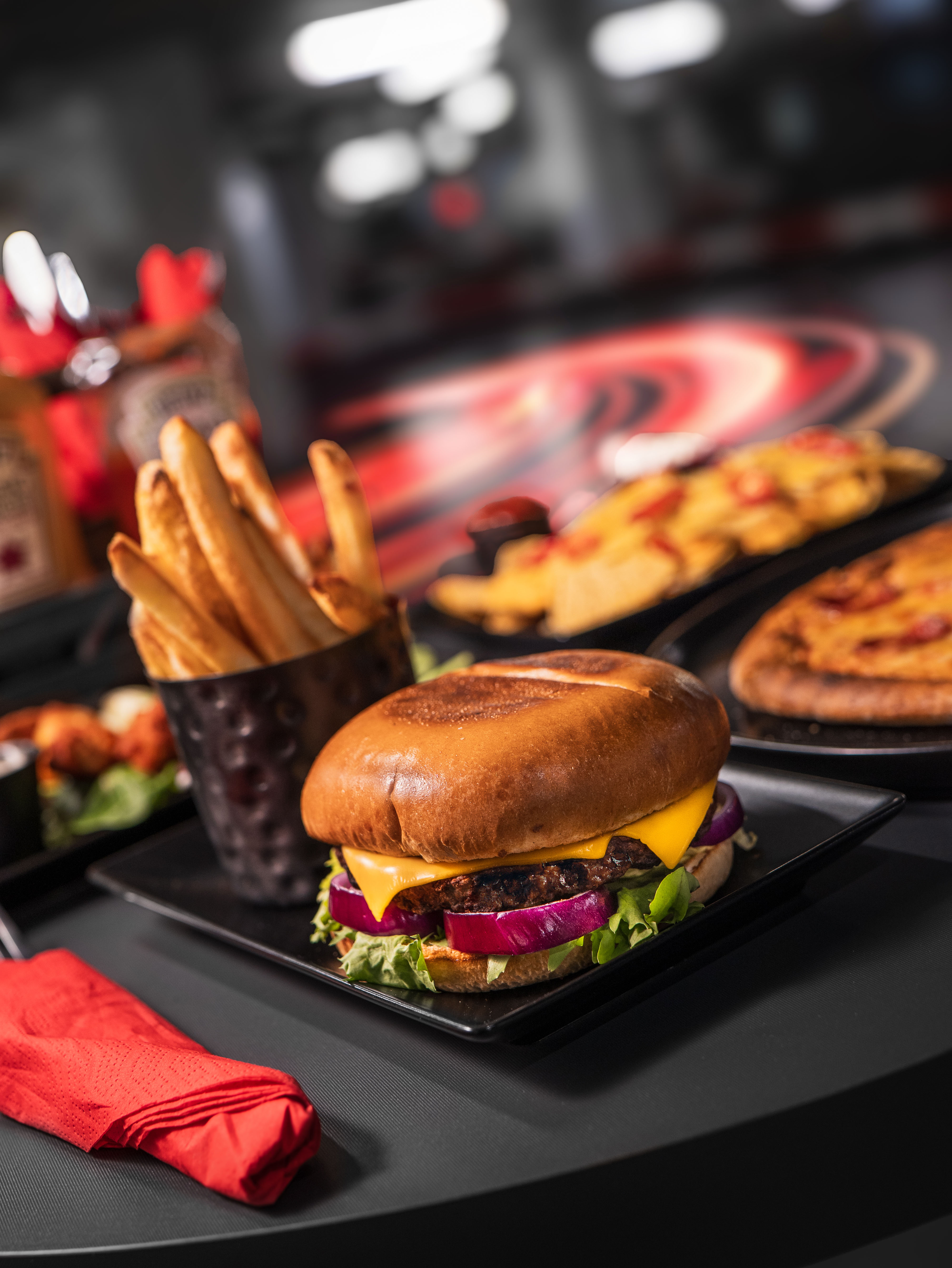 A close-up of a platter with a burger, fries, and a drink, all served in a casual dining setting.