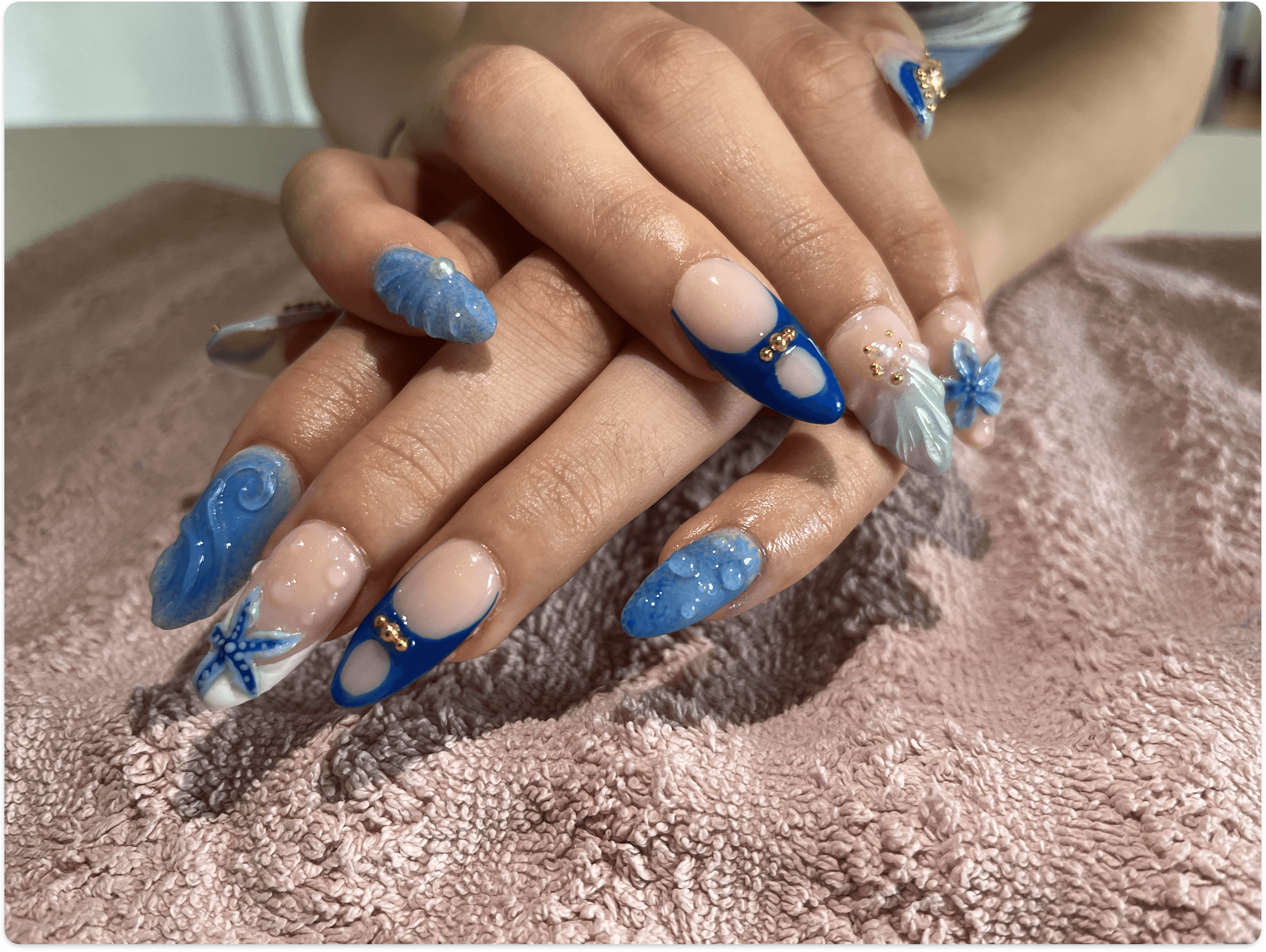 Hand with pink swirl nails and rings in car