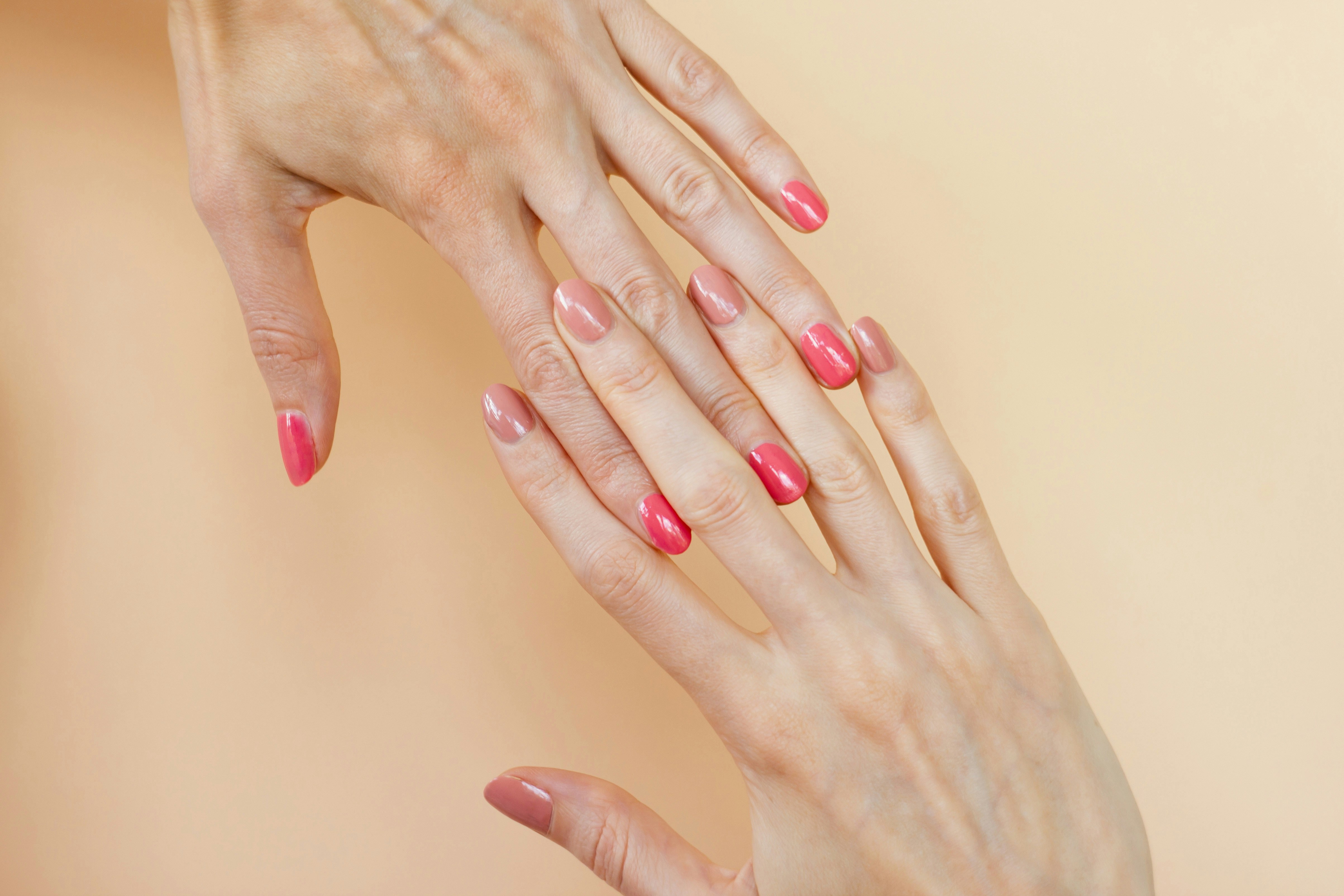 A woman's hands with pink manicures on them
