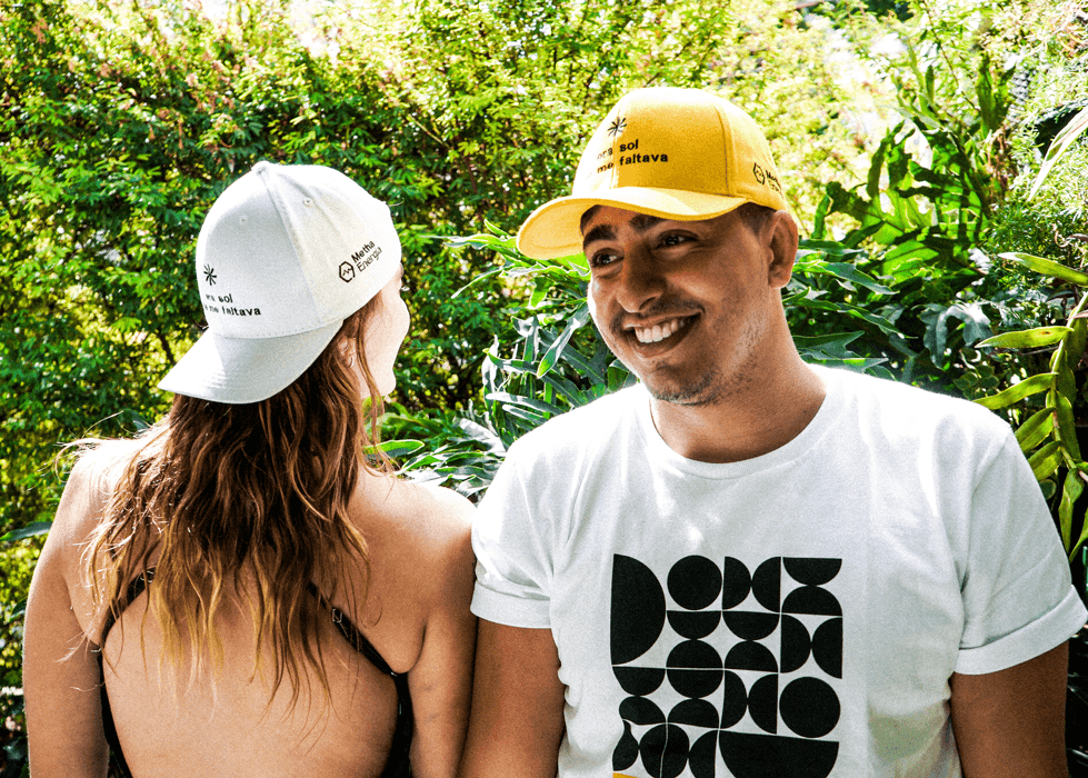 Pessoas sorrindo com boné e camiseta da Metha Energia