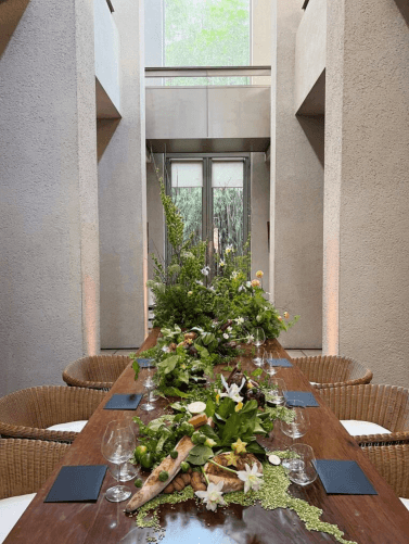 Mesa diseñada por Irina Khatsernova con centro floral orgánico y follaje — instalación botánica contemporánea para eventos.