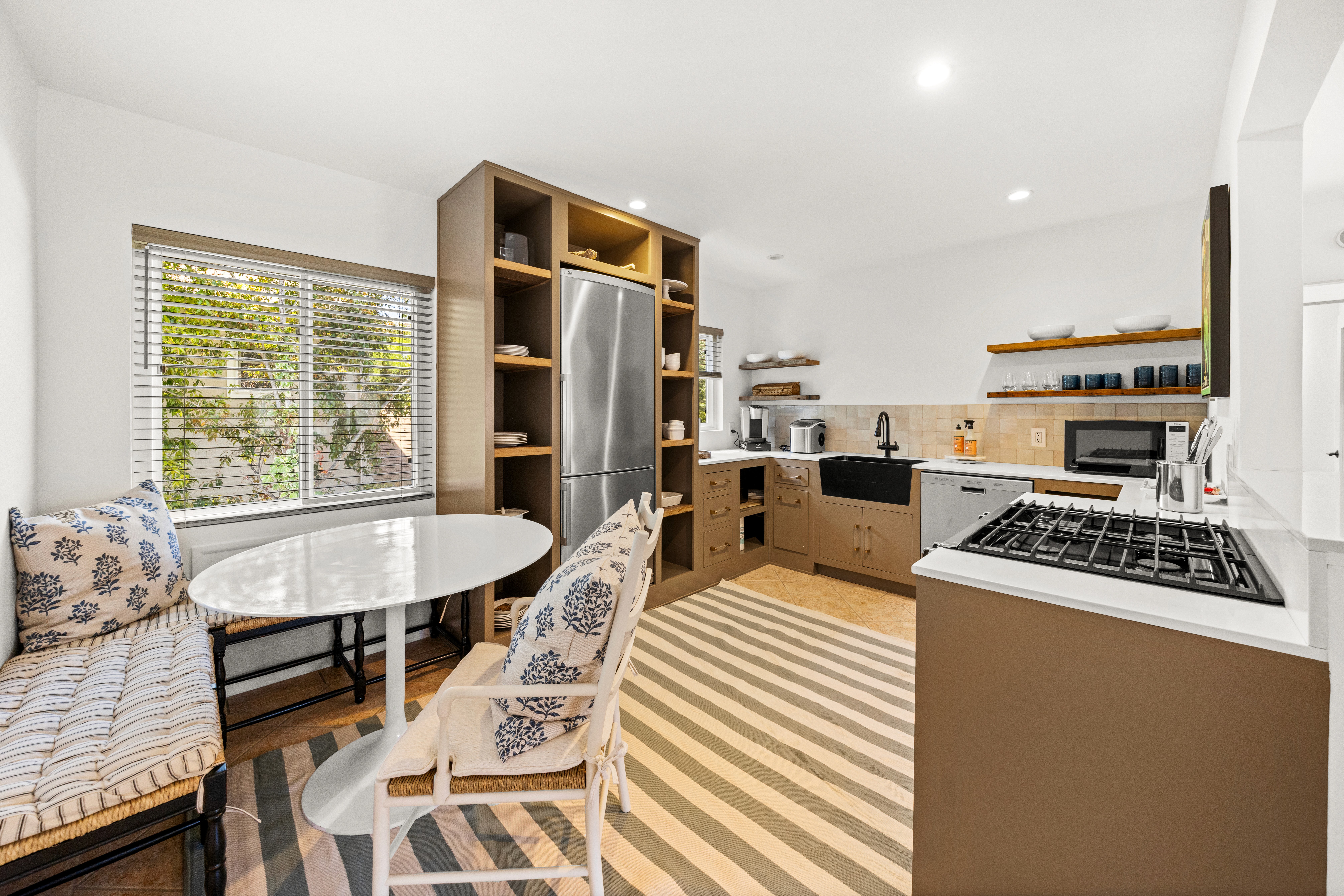 A fully updated kitchen with open shelving, modern appliances, and a cozy built-in dining nook.