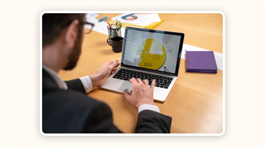 Man in a suit reviewing a yellow pie chart on a laptop screen, symbolizing real-time campaign traffic analysis and performance tracking.