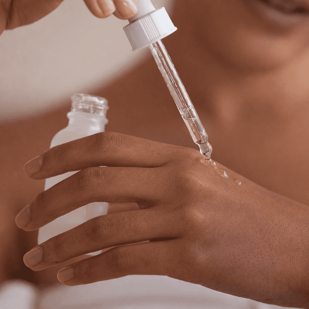 Close-up of a woman holding a dropper with skincare serum, preparing to apply it to her hand