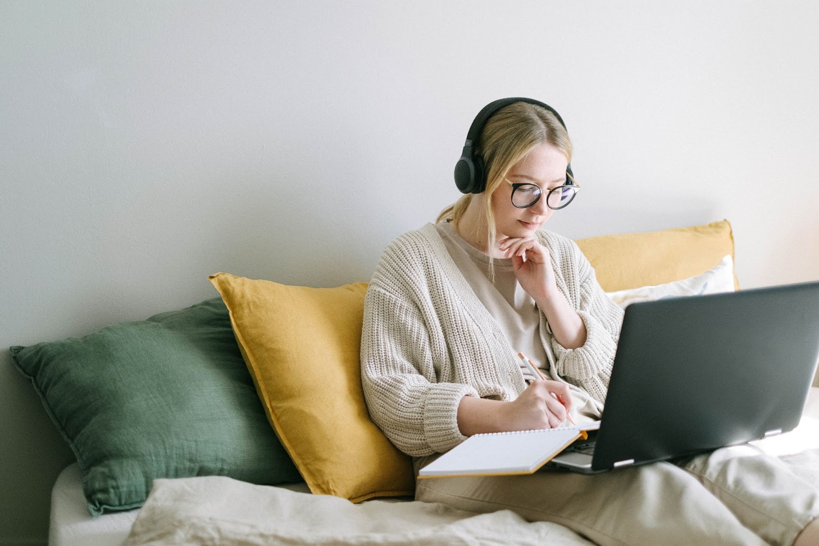 Woman studying with headphones, laptop, and notebook, representing deep work.