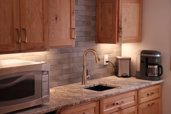 Kitchen sink with slate backsplash and light wood cabinets