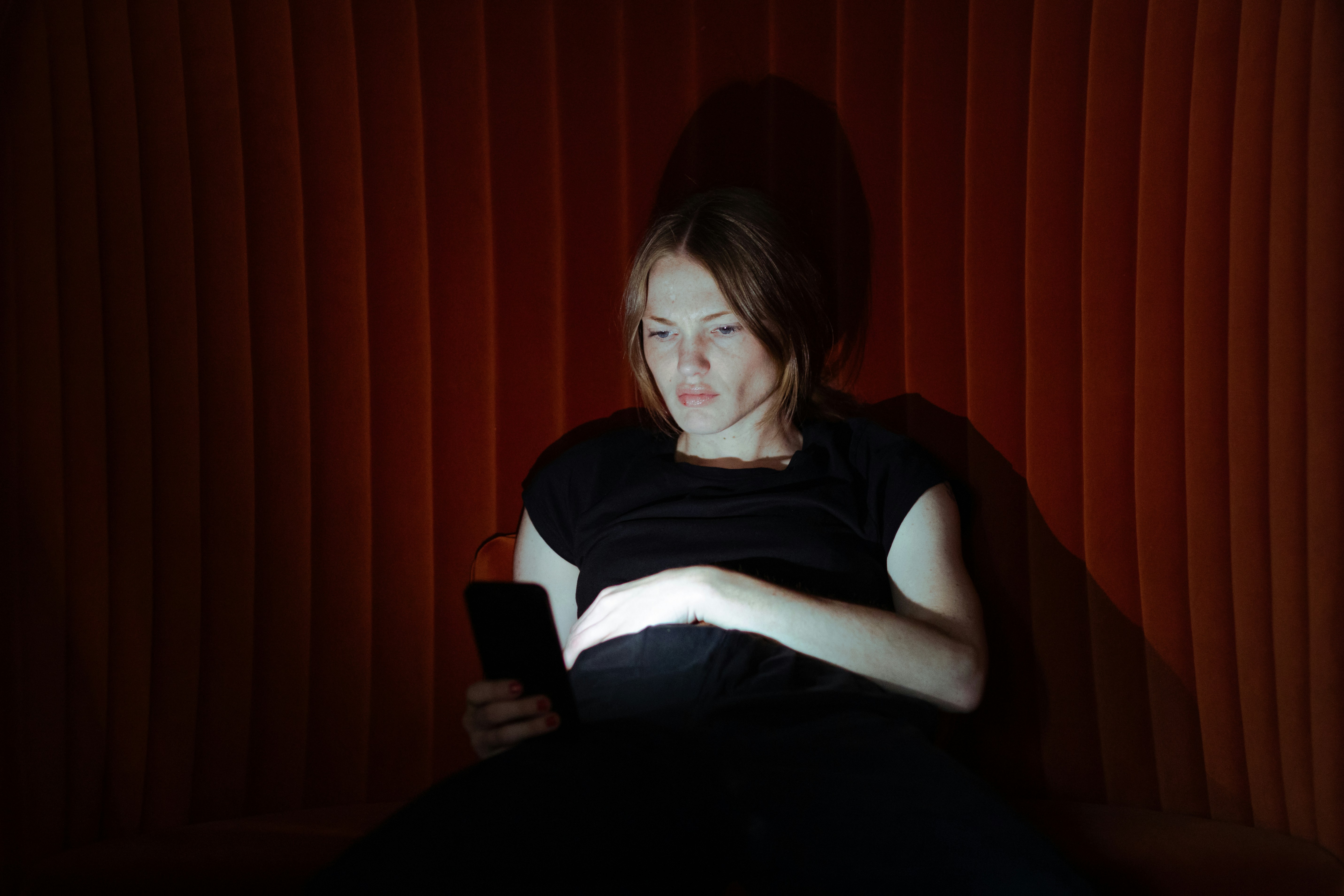 woman in dark and staring at phone