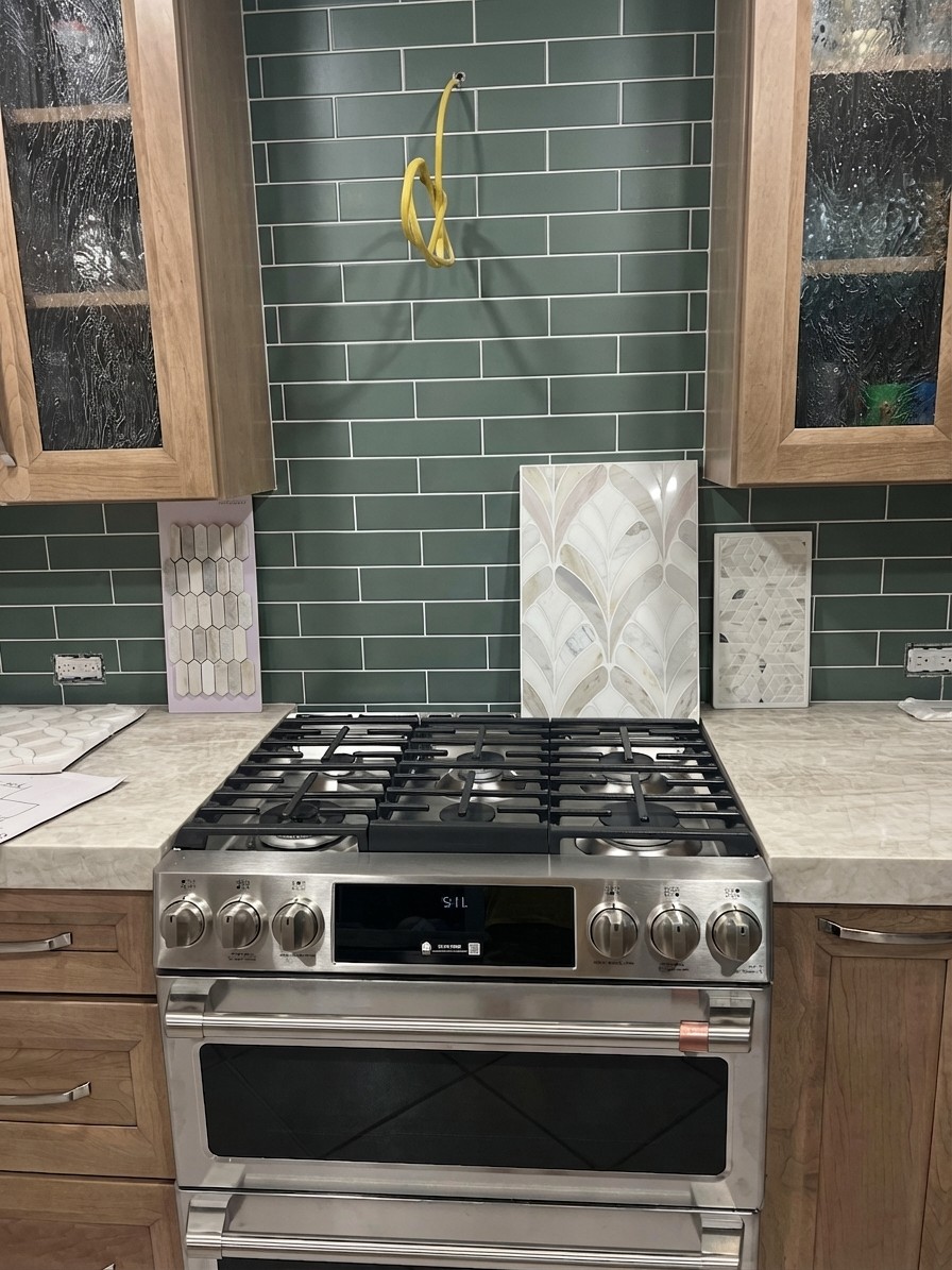 Deep sage green subway tile creating moody contrast against cream and honey tones