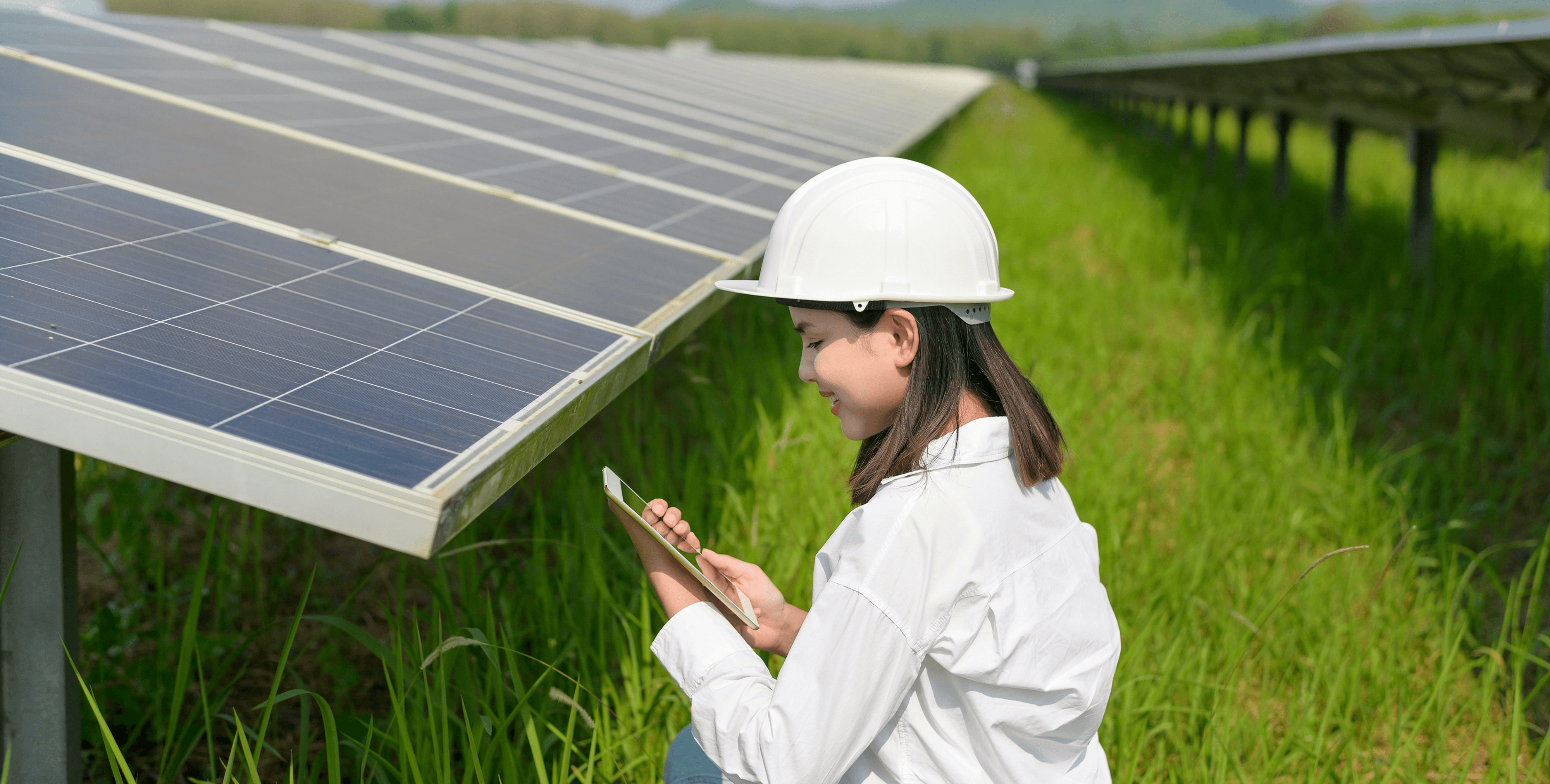 Woman in hard hat checks tablet near solar panels