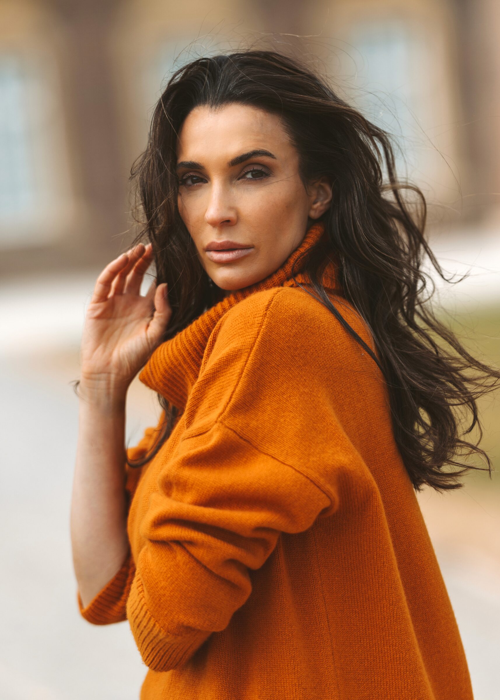 Woman with dark hair in an orange turtleneck cashmere jumper