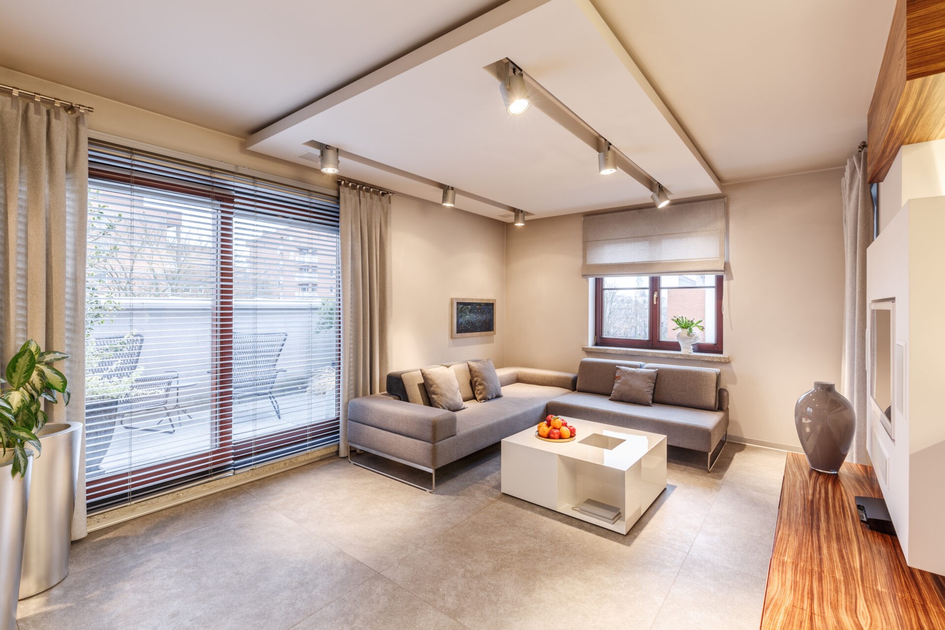 Spacious, brown theme living room interior design with sofa, large sliding door with roman shades. Wholesale Blind Factory