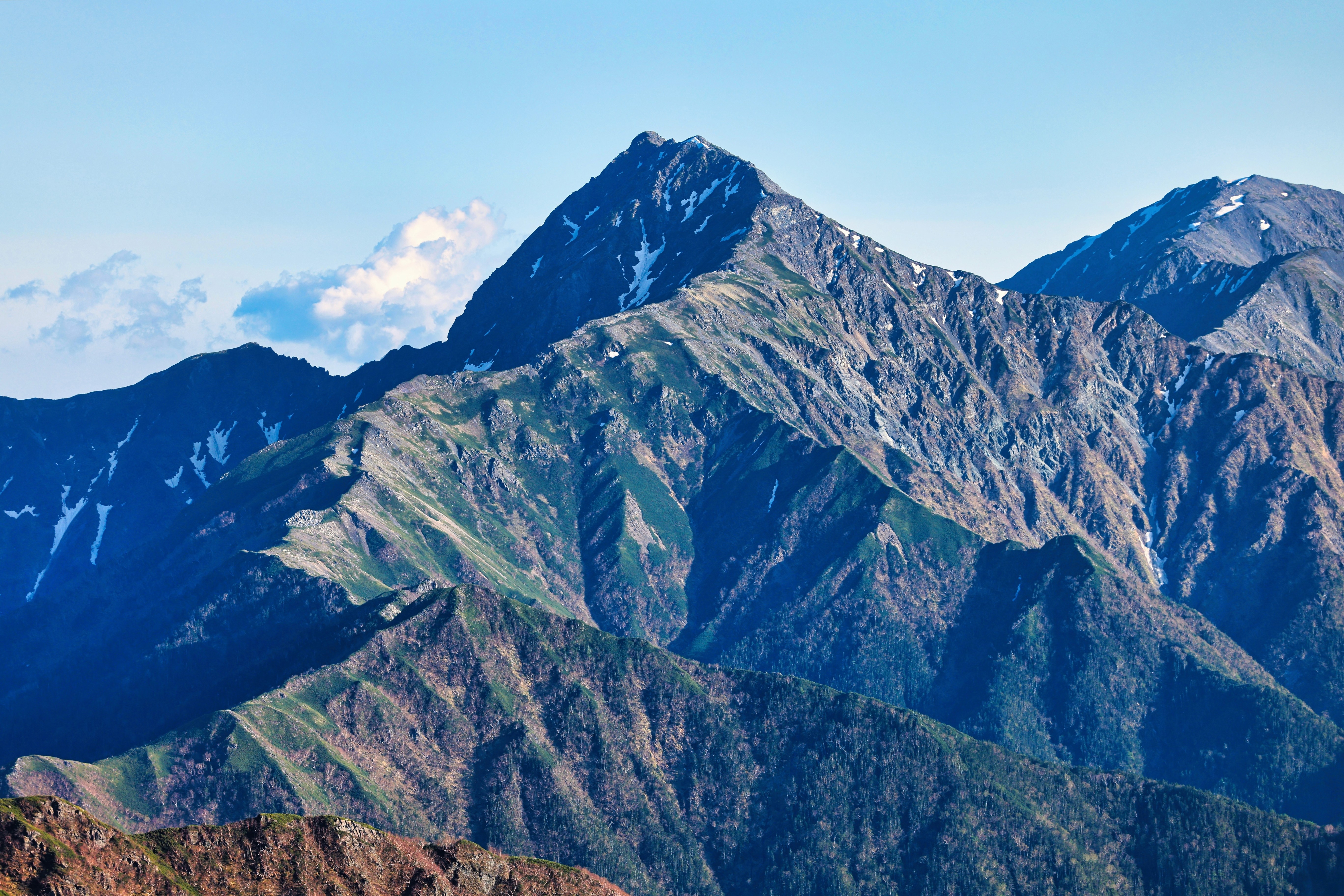 The snaking ridge to the peak of Mt Kita, Japan, with the blue sky behind the summit