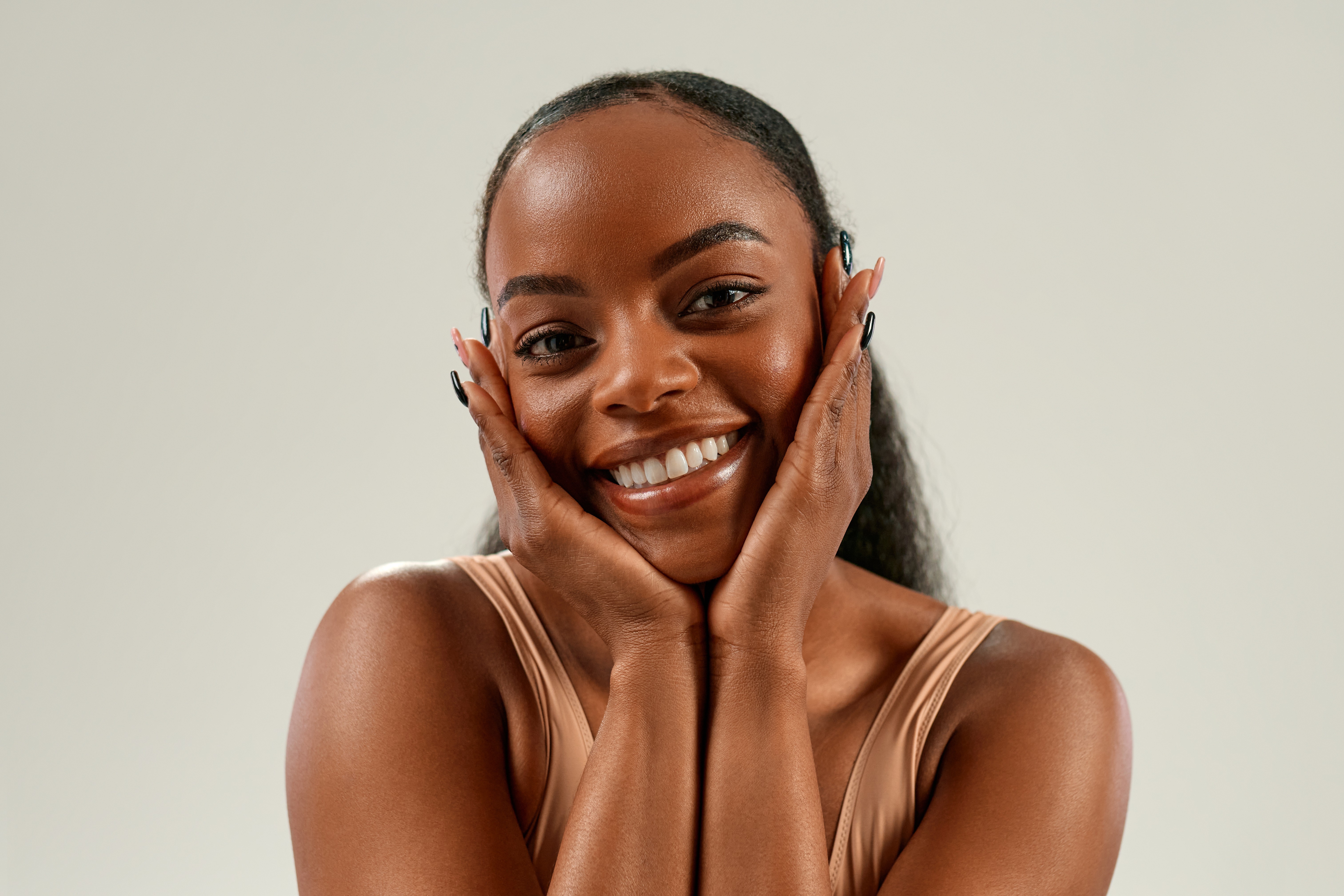 Woman in a towel and head wrap applying skincare cream in a cozy bedroom