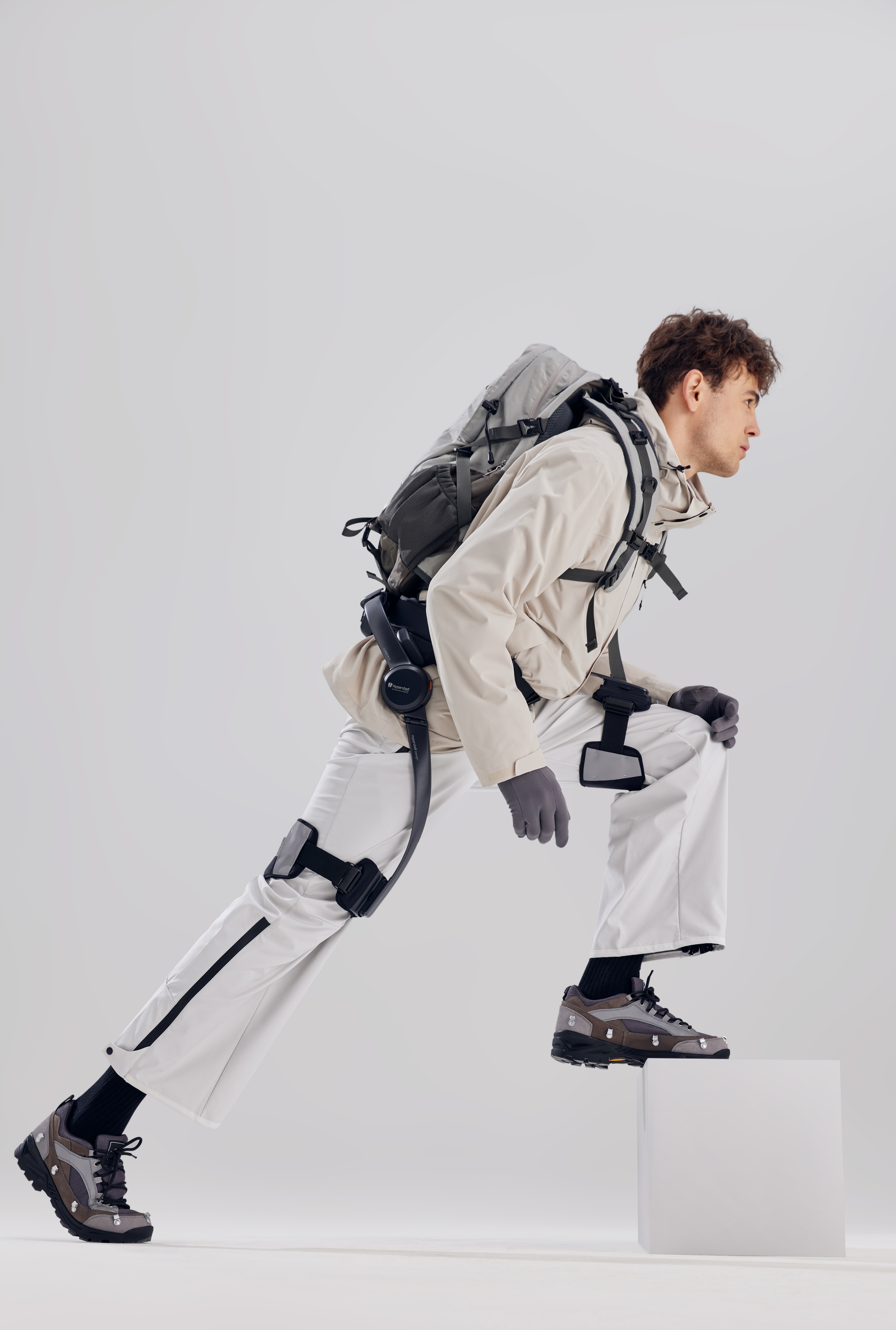 Homme équipé de l’exosquelette Hypershell X Pro montant une marche avec sac à dos, démontrant l’assistance à la marche et la réduction de la fatigue.