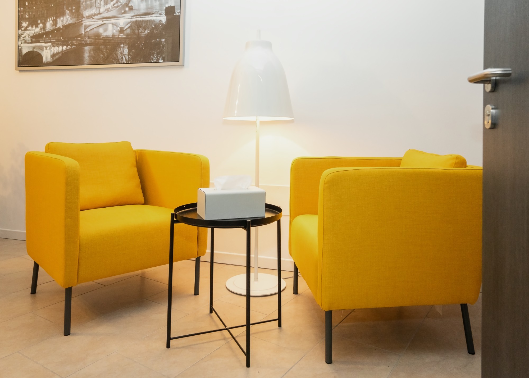 Due comode poltrone gialle e un tavolino con una scatola di fazzoletti in un angolo accogliente dello studio di psicologia