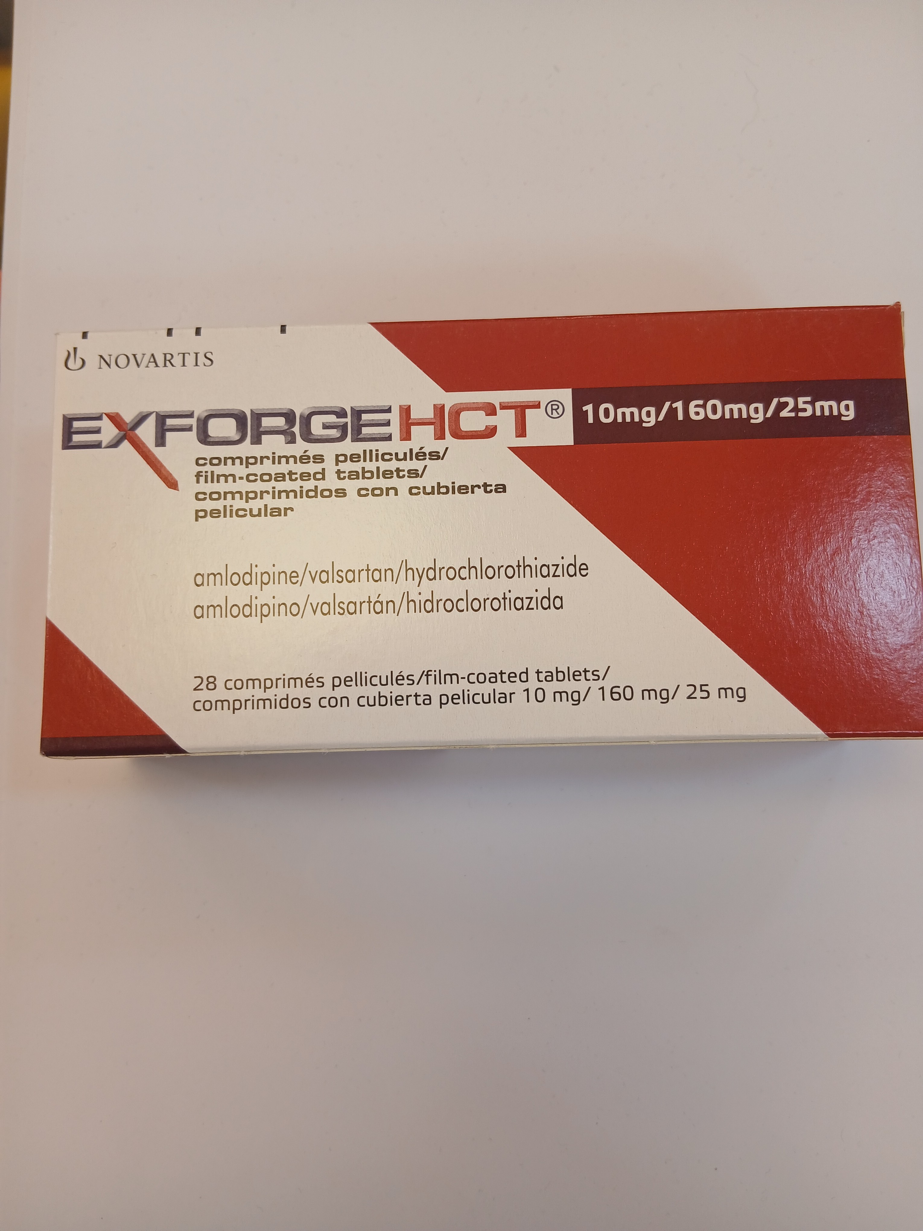 A red and white cardboard box packaging displays film-coated tablets with printed text in multiple languages, listing dosages of 10 mg/160 mg/25 mg.