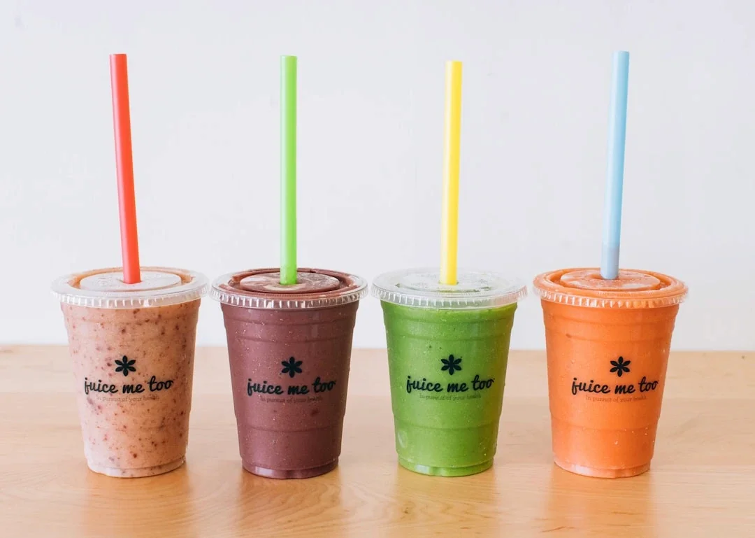 three cups of smoothie with straws on a table