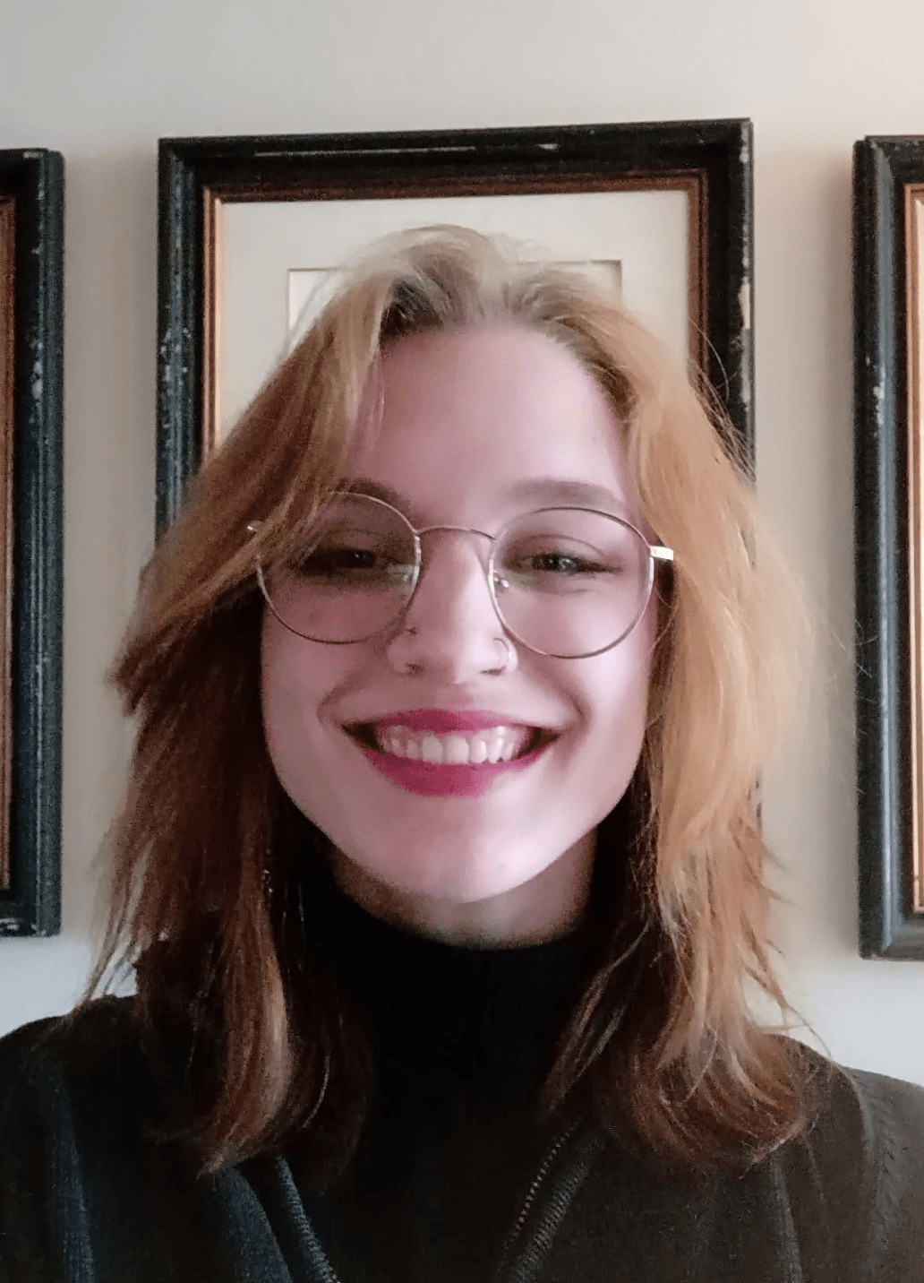 A close-up portrait photograph of Skyler Koba smiling, with mid-length brown hair, wearing glasses and a quarterzip.