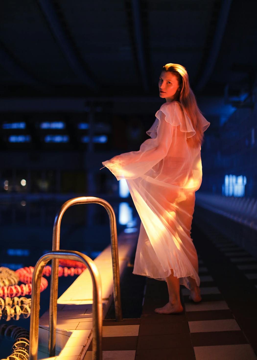 Woman looking back to the camera next to a swimming pool