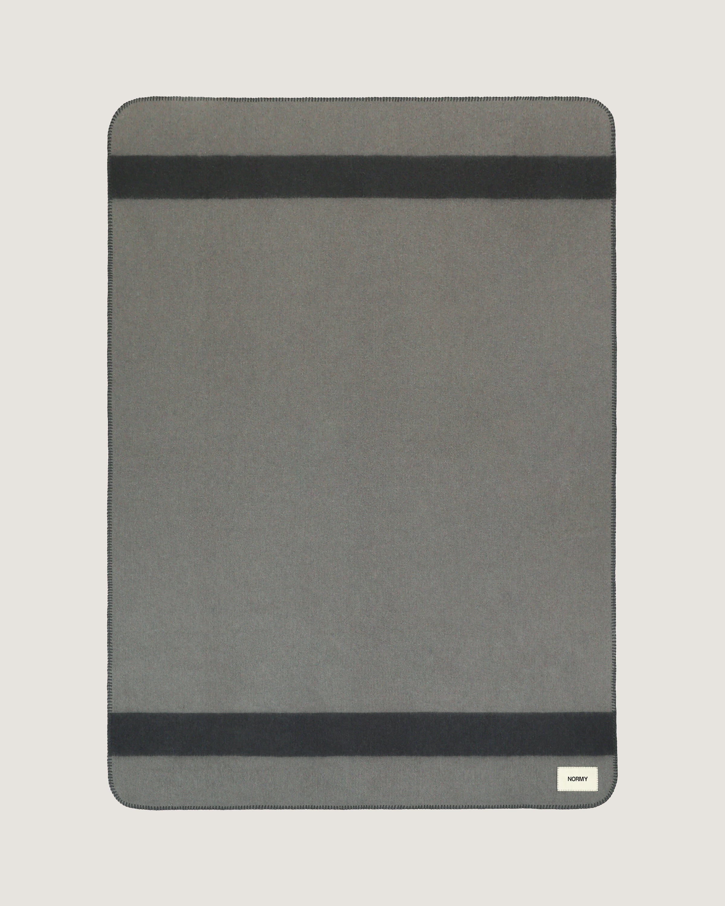 Merino wool blanket in peak/caviar flat against a neutral background
