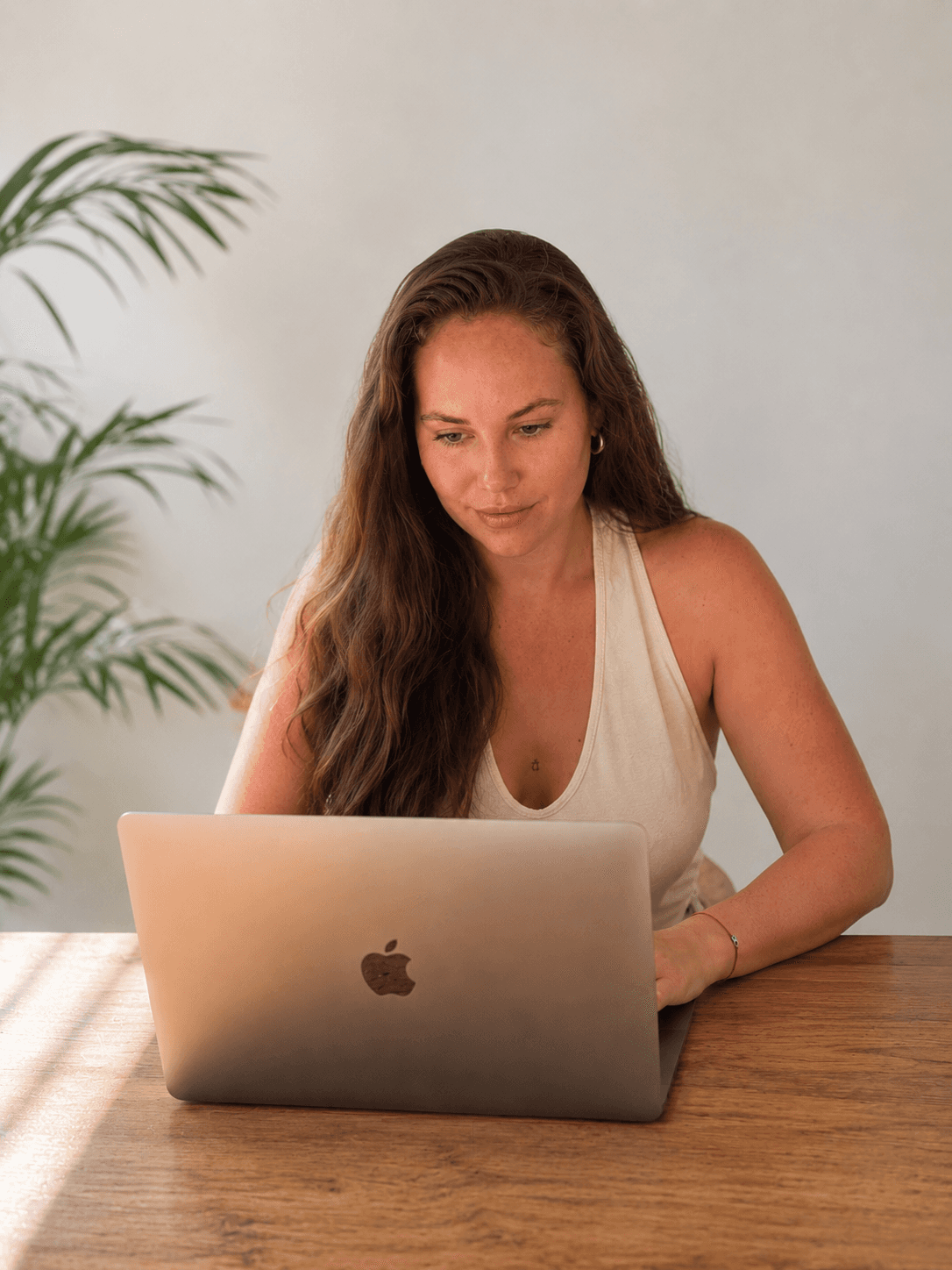 Neline seated with laptop in a warm professional portrait