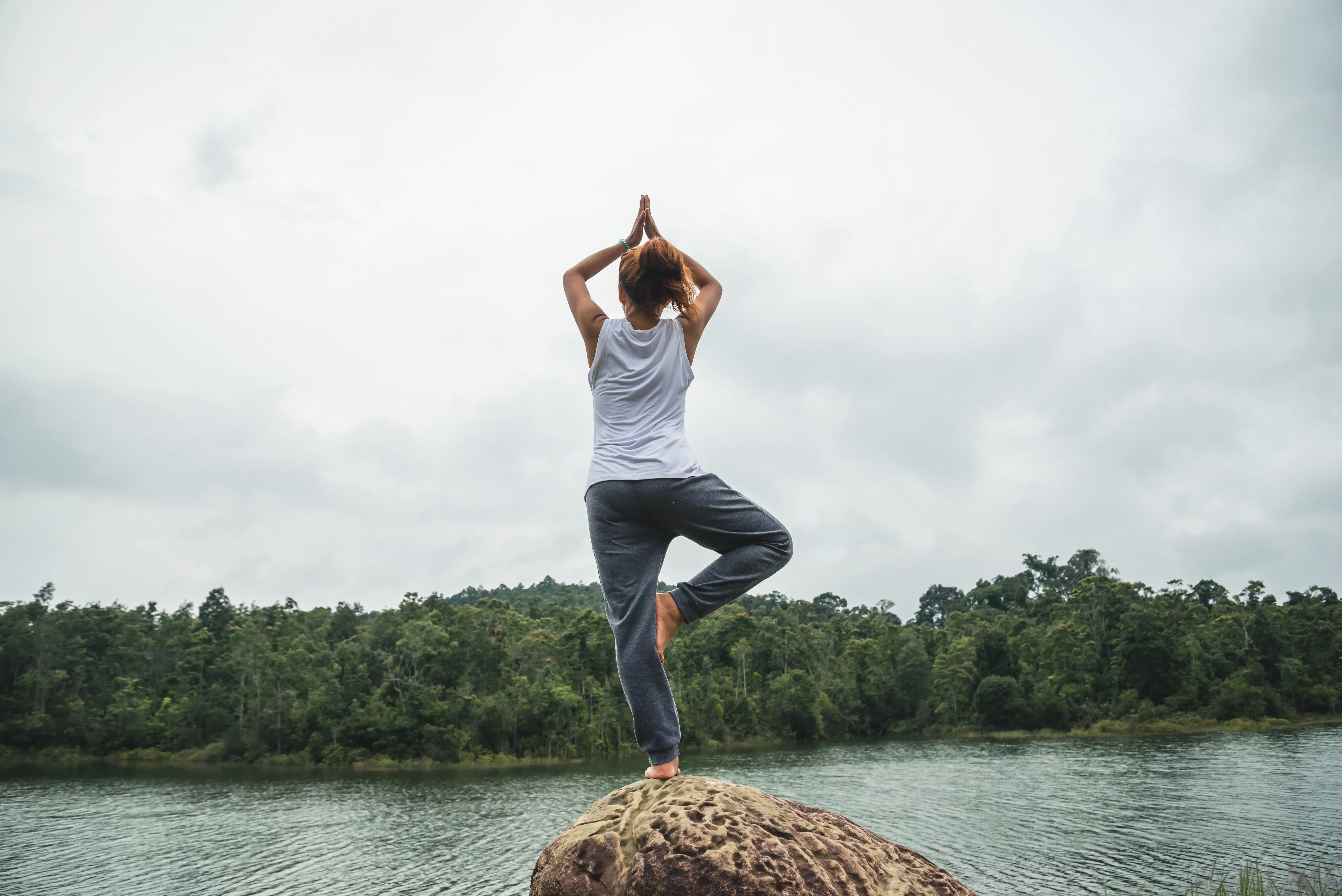 Persona practicando postura de yoga al aire libre, conectando cuerpo y mente en equilibrio con la naturaleza