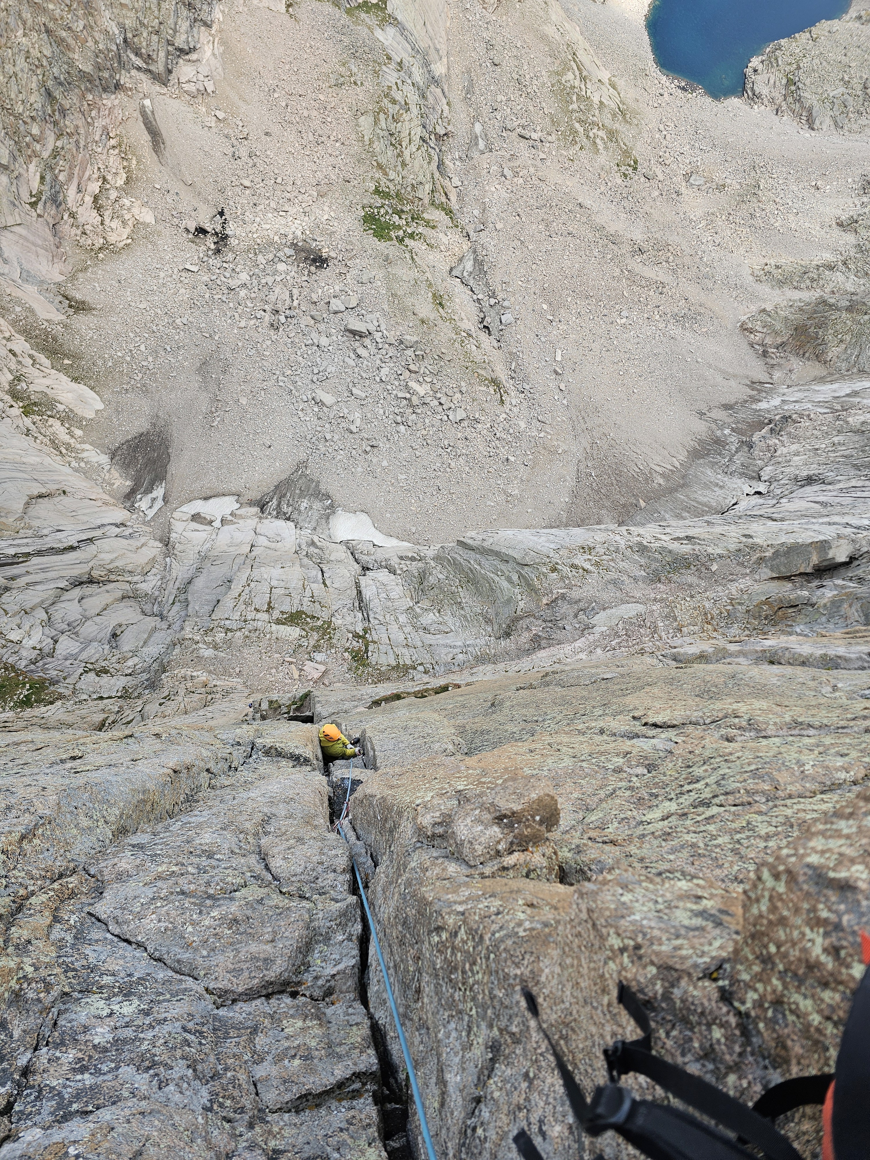 climber in yellow follows the crux pitch of Casual route on the diamond with chasm lake in the background