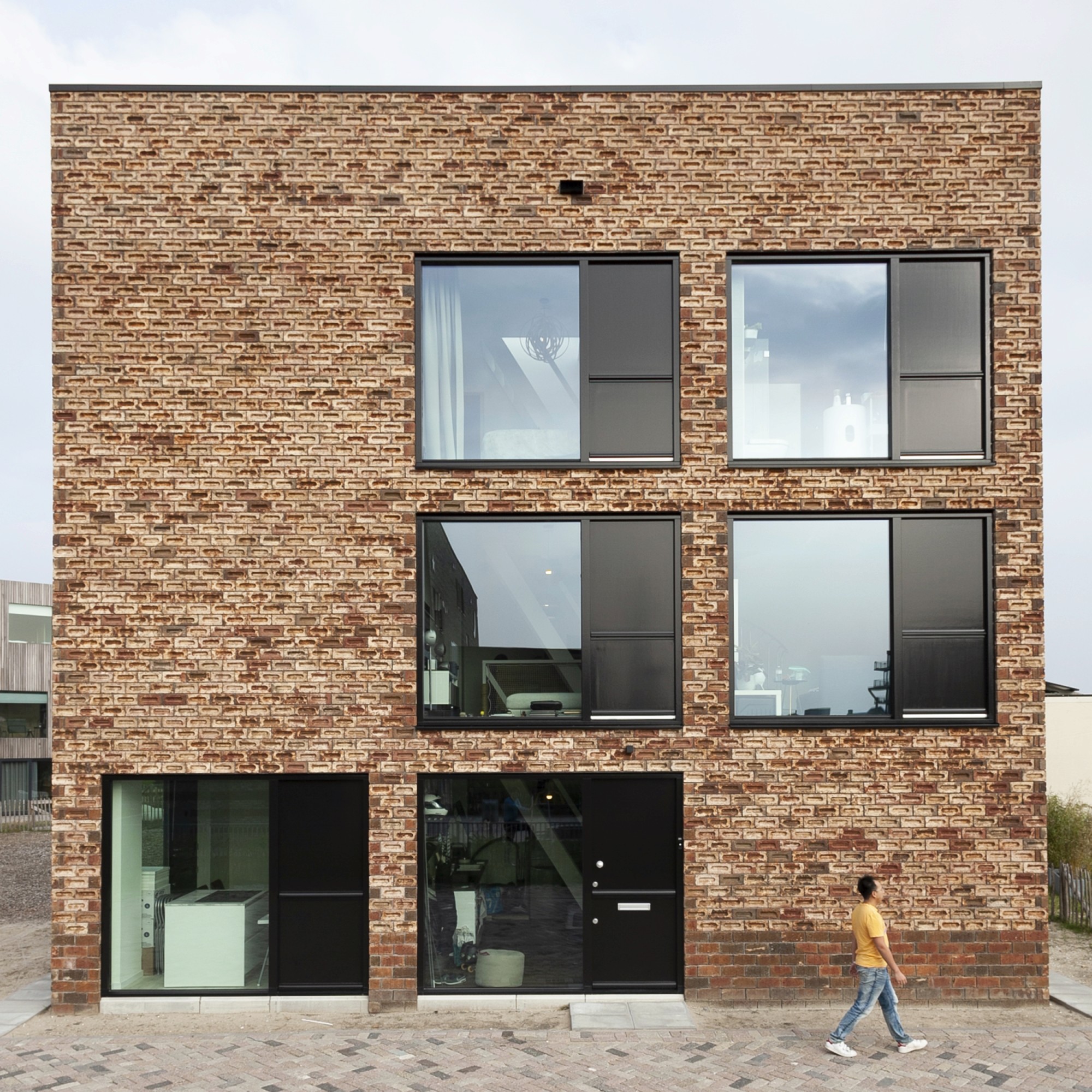 Modern bakstenen gebouw met grote ramen en zwarte kozijnen.