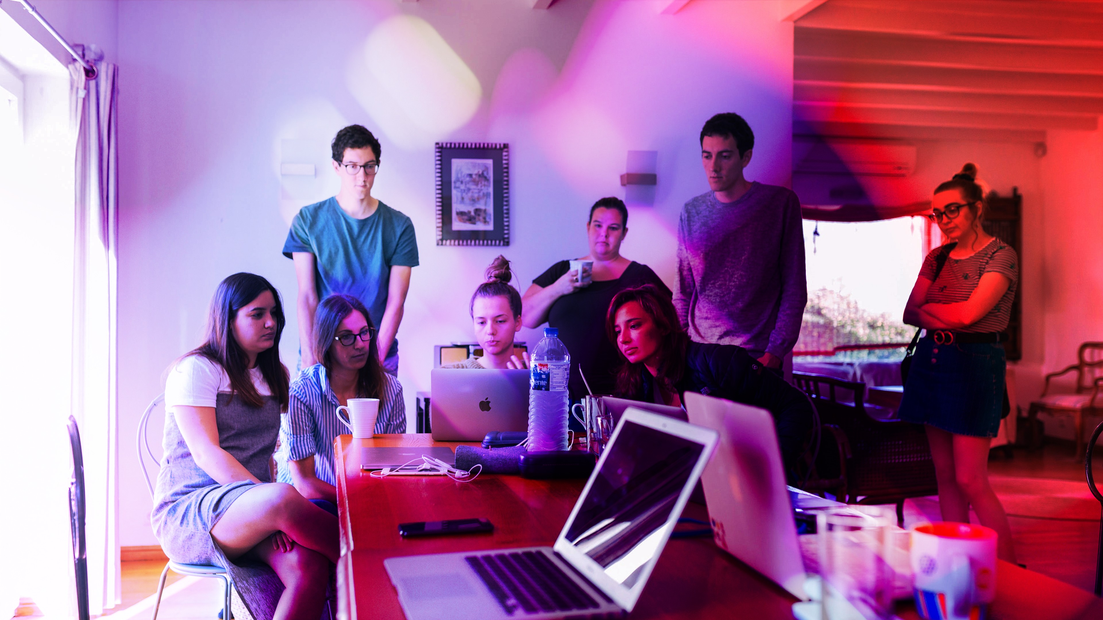 A group of people all looking at a single laptop