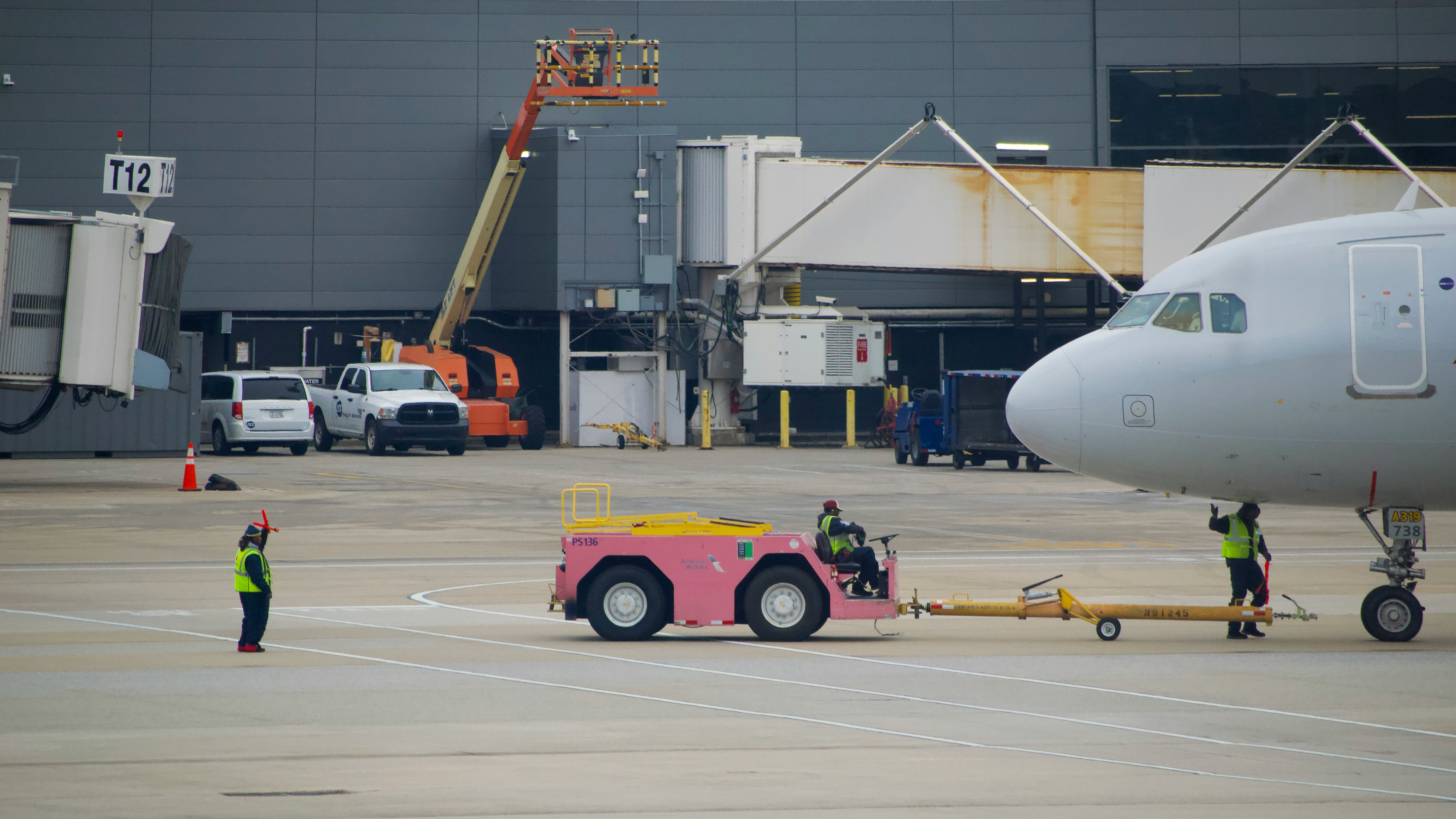 Airport workers guide airplane with tow tractor