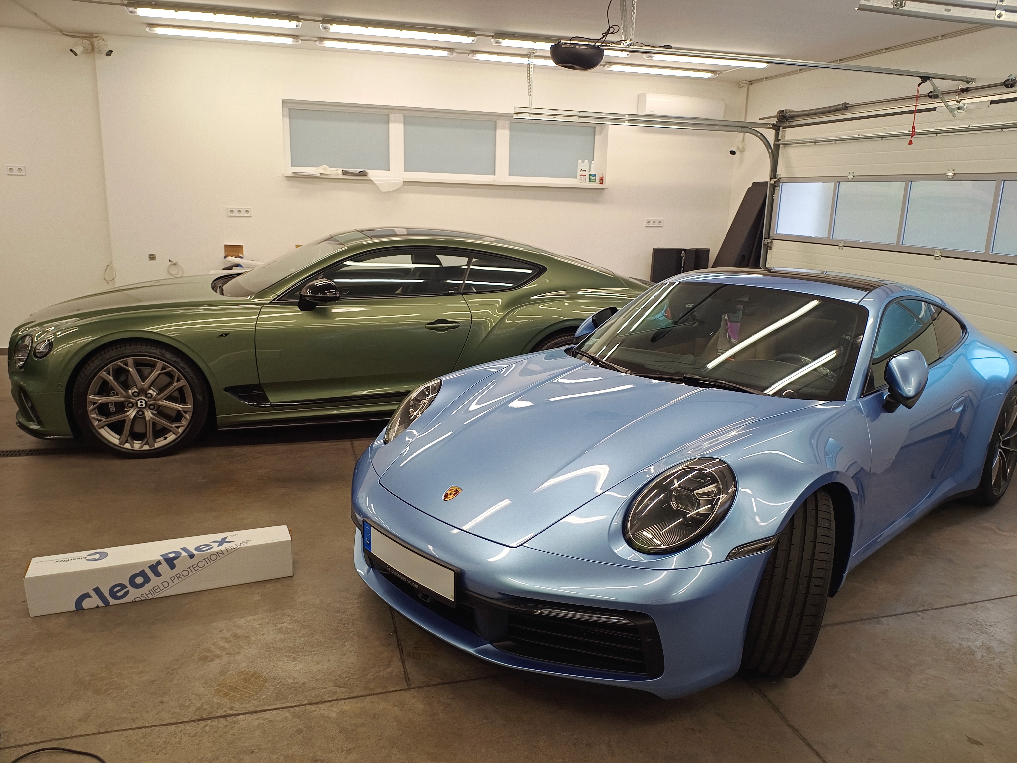 Világoskék Porsche 911 sportautó és zöld Bentley Continental luxusautó kompromisszummentes színváltó autófóliázás (wrap) után a Nortek stúdiójában.