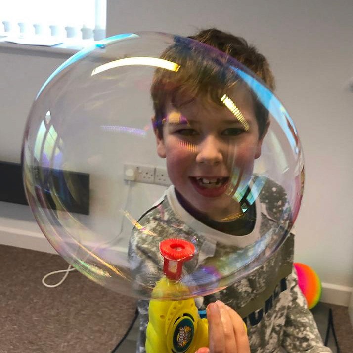 A child is using a bubble gun to blow bubbles