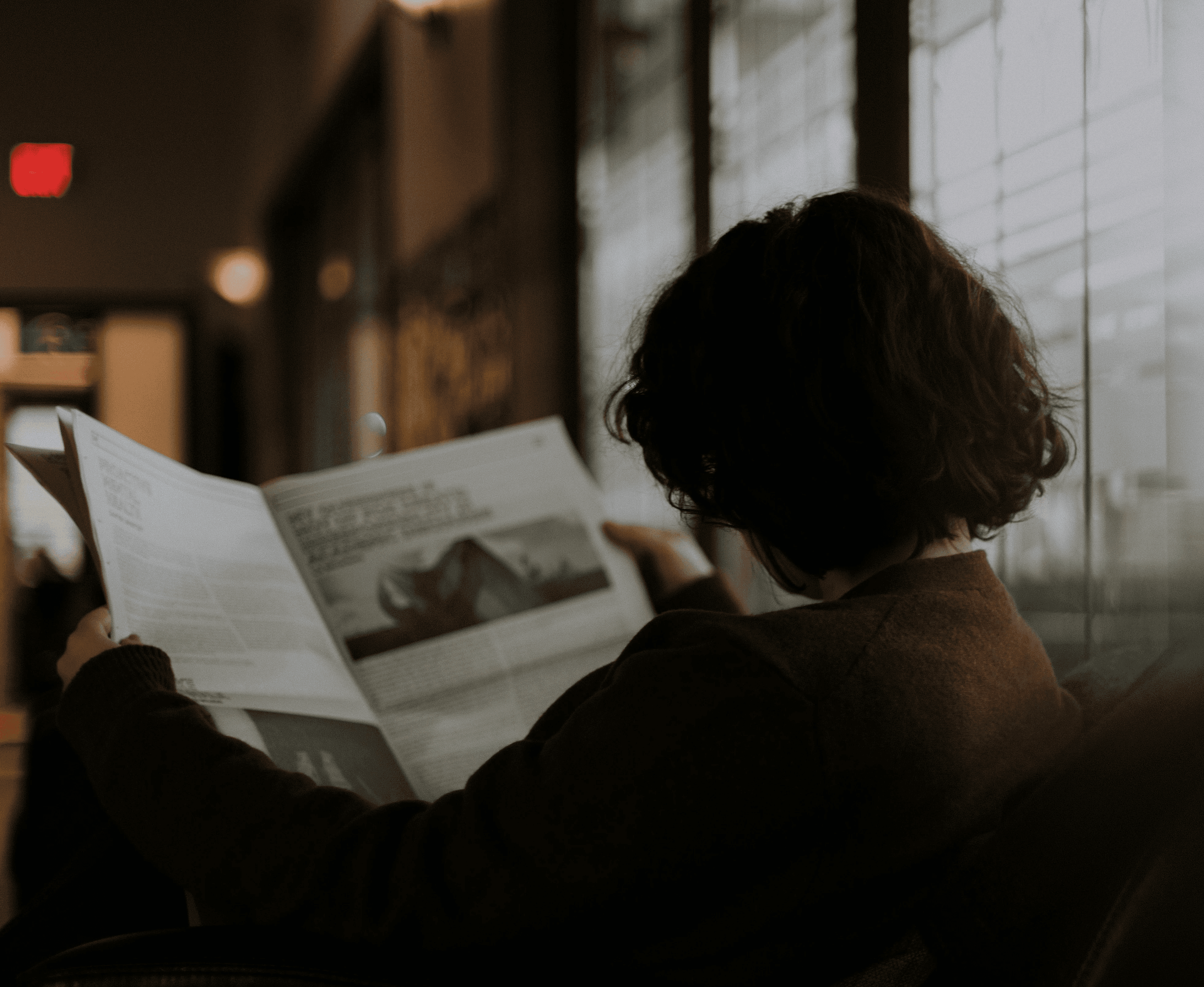 woman in brown long sleeve shirt sitting by the window