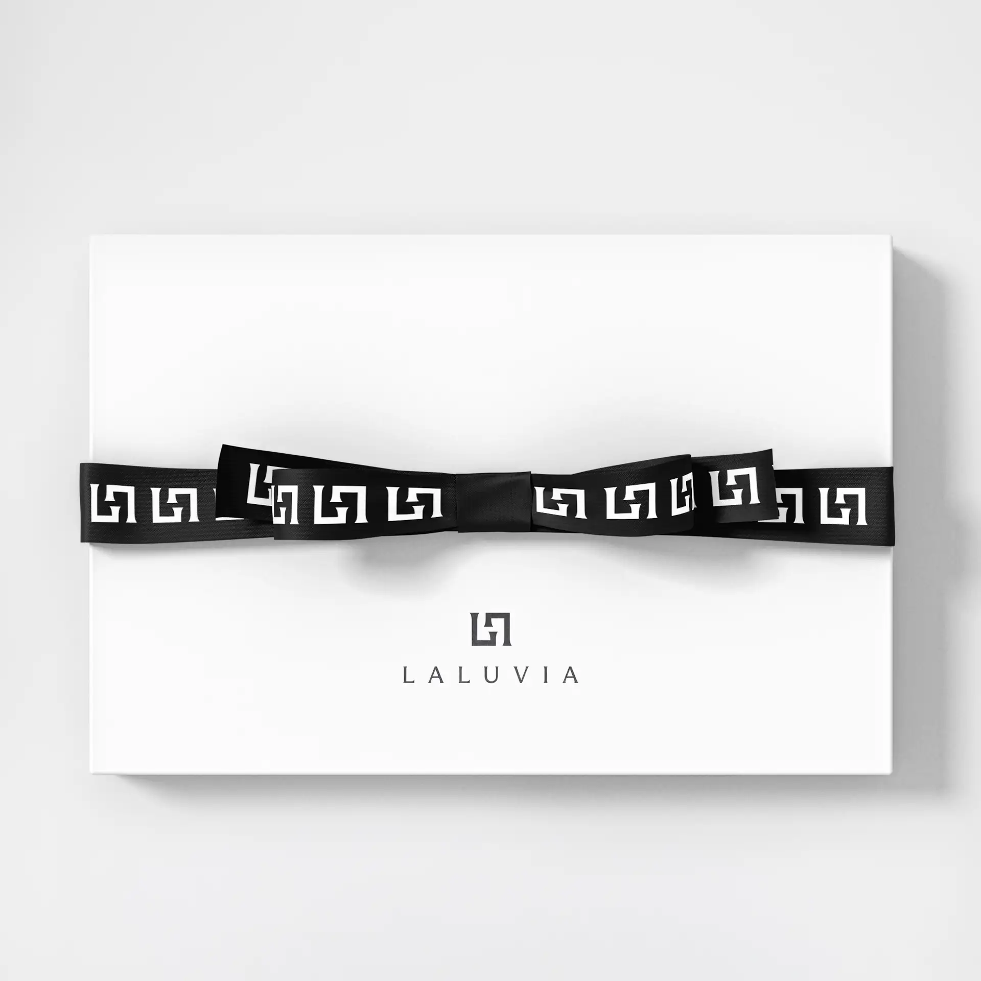 Premium white Laluvia gift box tied with a branded black ribbon displaying a monogram pattern.