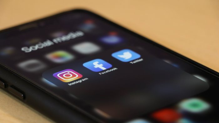 Smartphone screen showing Instagram, Facebook, and Twitter icons grouped under a folder labeled "Social Media."