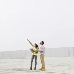 Auditor with a clipboard pointing something out to a site supervisor