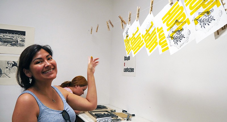 Student putting some posters to dry on a wire.