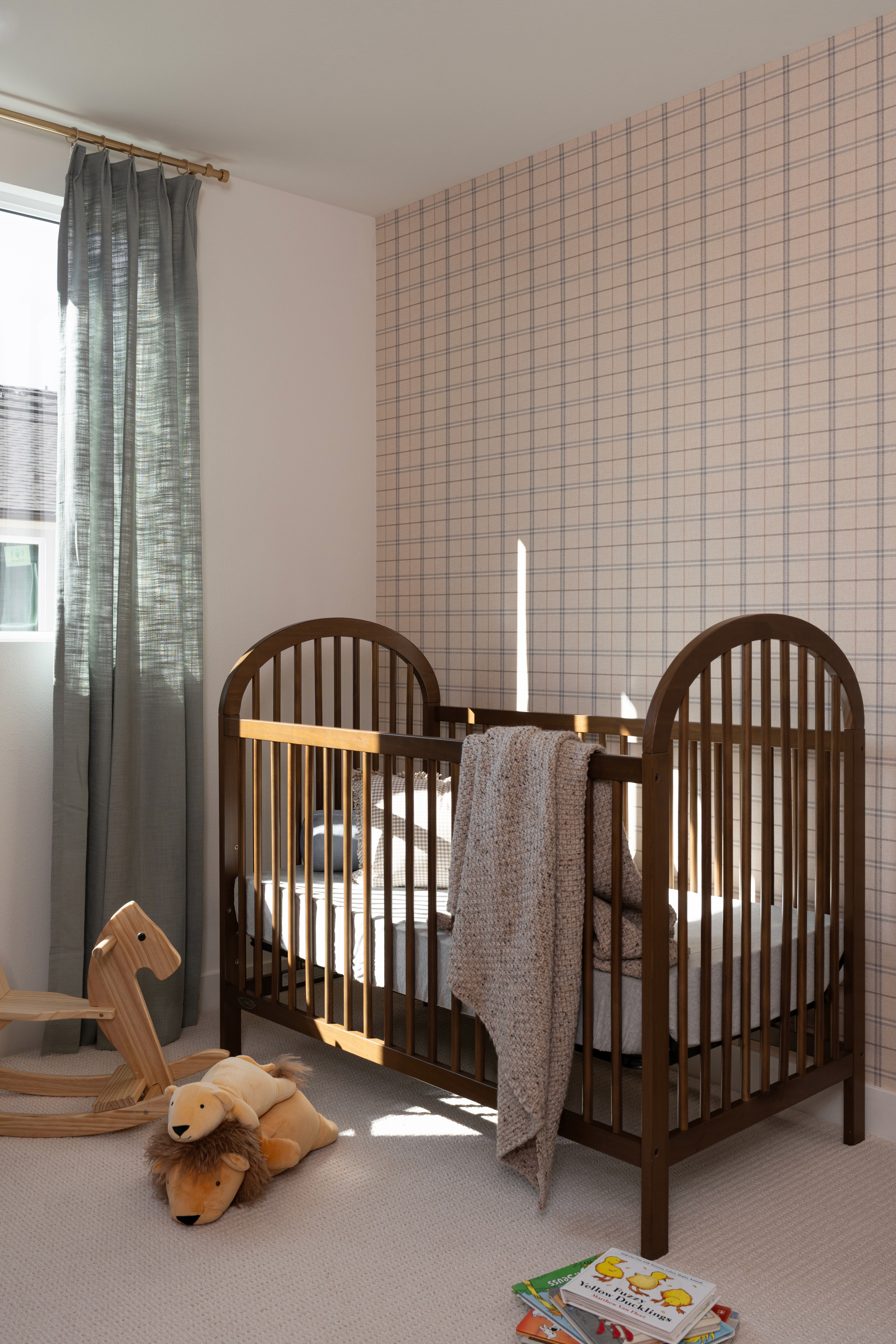 View of crib in nursery with rocking horse, stuffed animals and books