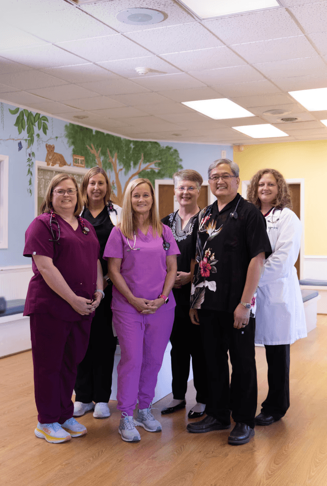 Team of six Pediatricians and Nurse Practitioners smiling in the lobby.