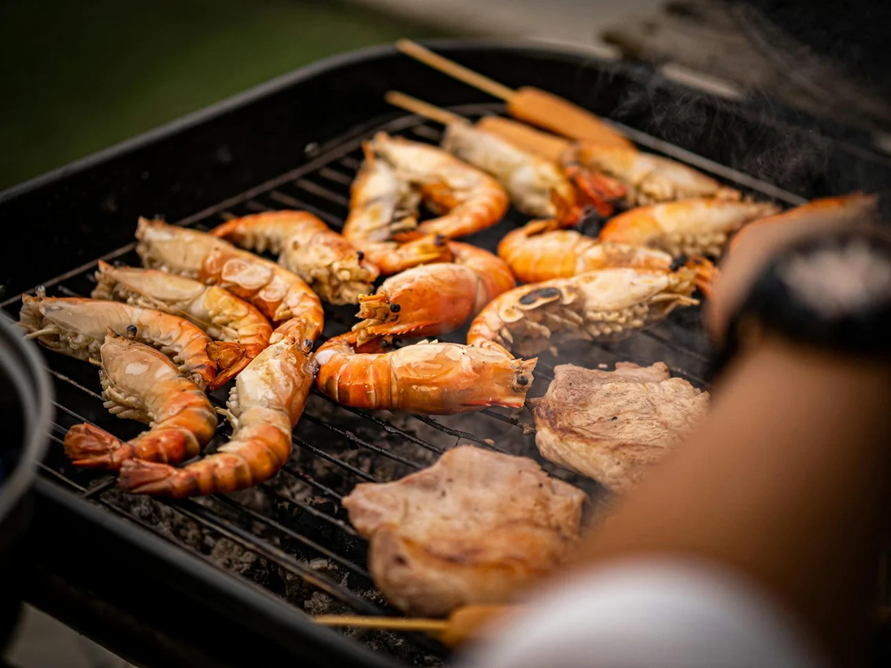 Fresh prawns, seafood, and grilled dishes cooking on a barbecue grill.