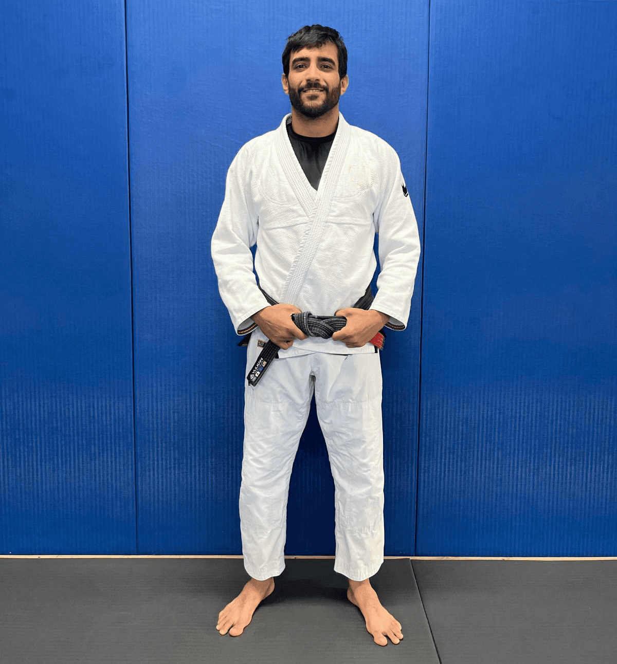 Maria Elisa Thimoteo smiling in her gi, hands folded in front of a gradient backdrop