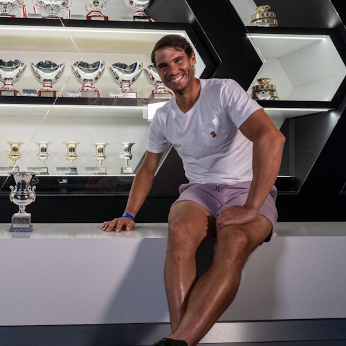 Rafa Nadal posant avec l'un des trophées remportés à Rome, avec la vitrine contenant le reste des trophées en arrière-plan.