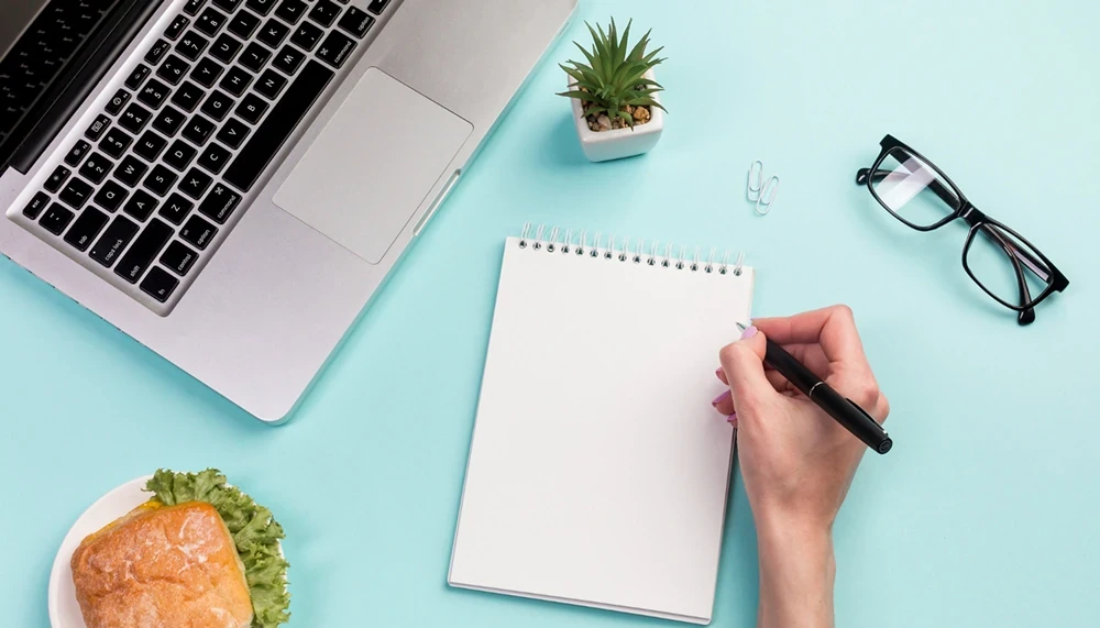 A hand is holding a pen over a notepad