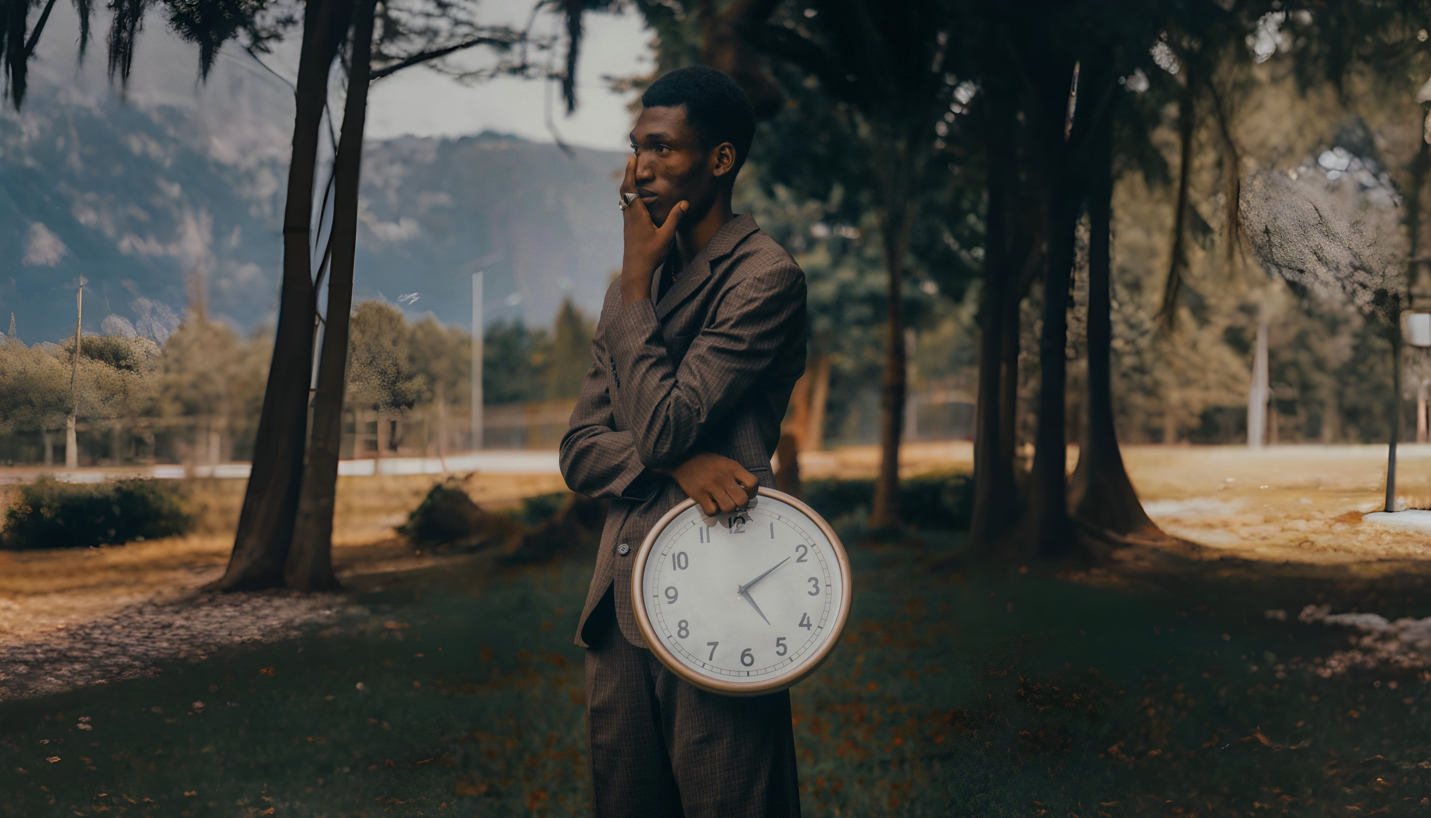 Man holding a clock while posing in a field.