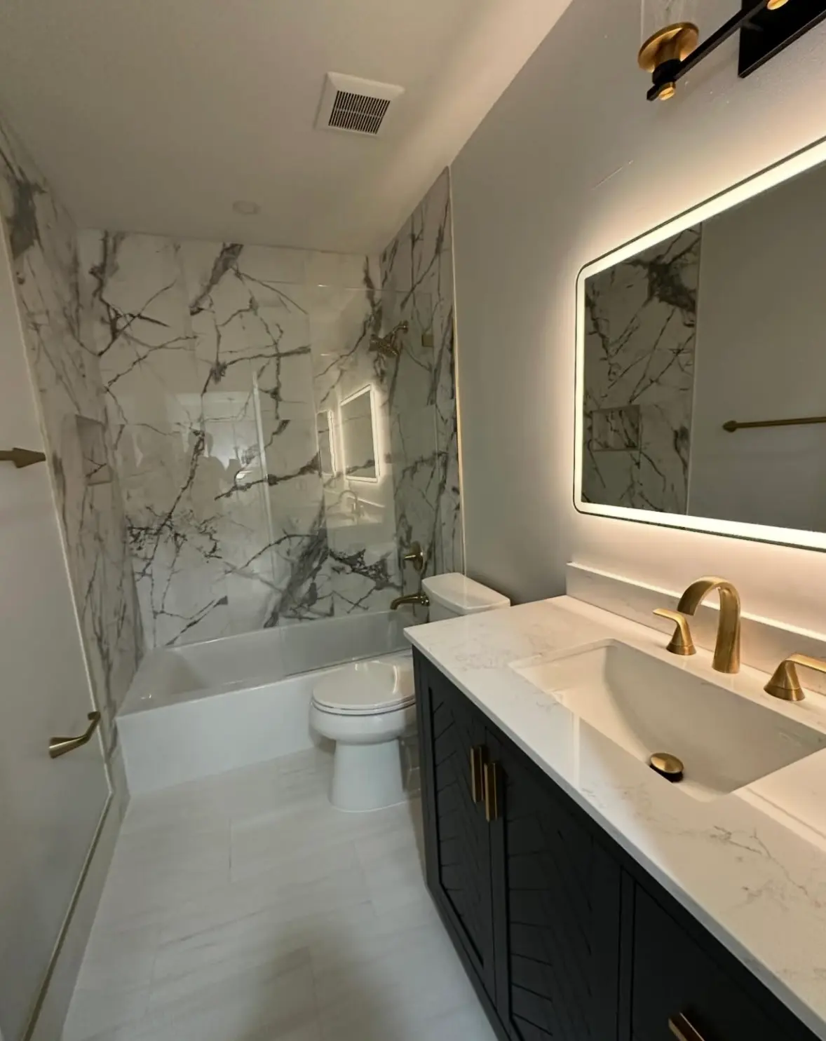 A fully sanitized and deep-cleaned bathroom with marble wall tiles, polished gold fixtures, and a spotless white floor, ready for a new move-in.