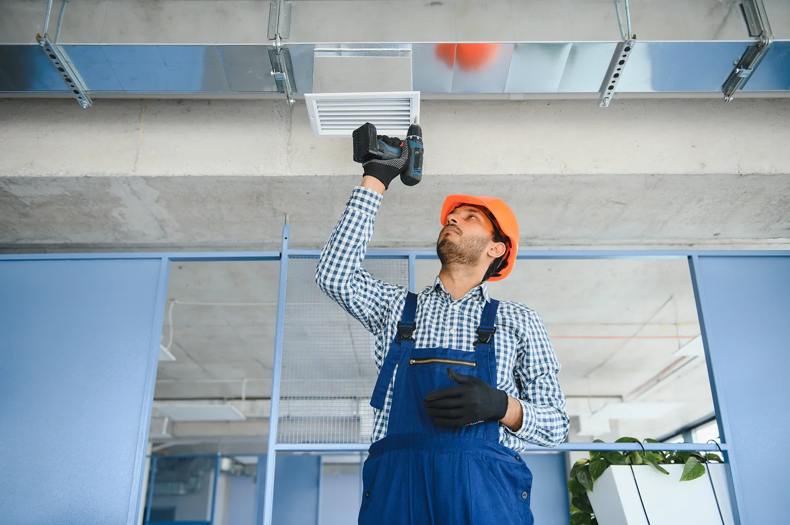 Professional technician installing a white ductless mini-split air conditioning system on an exterior wall.