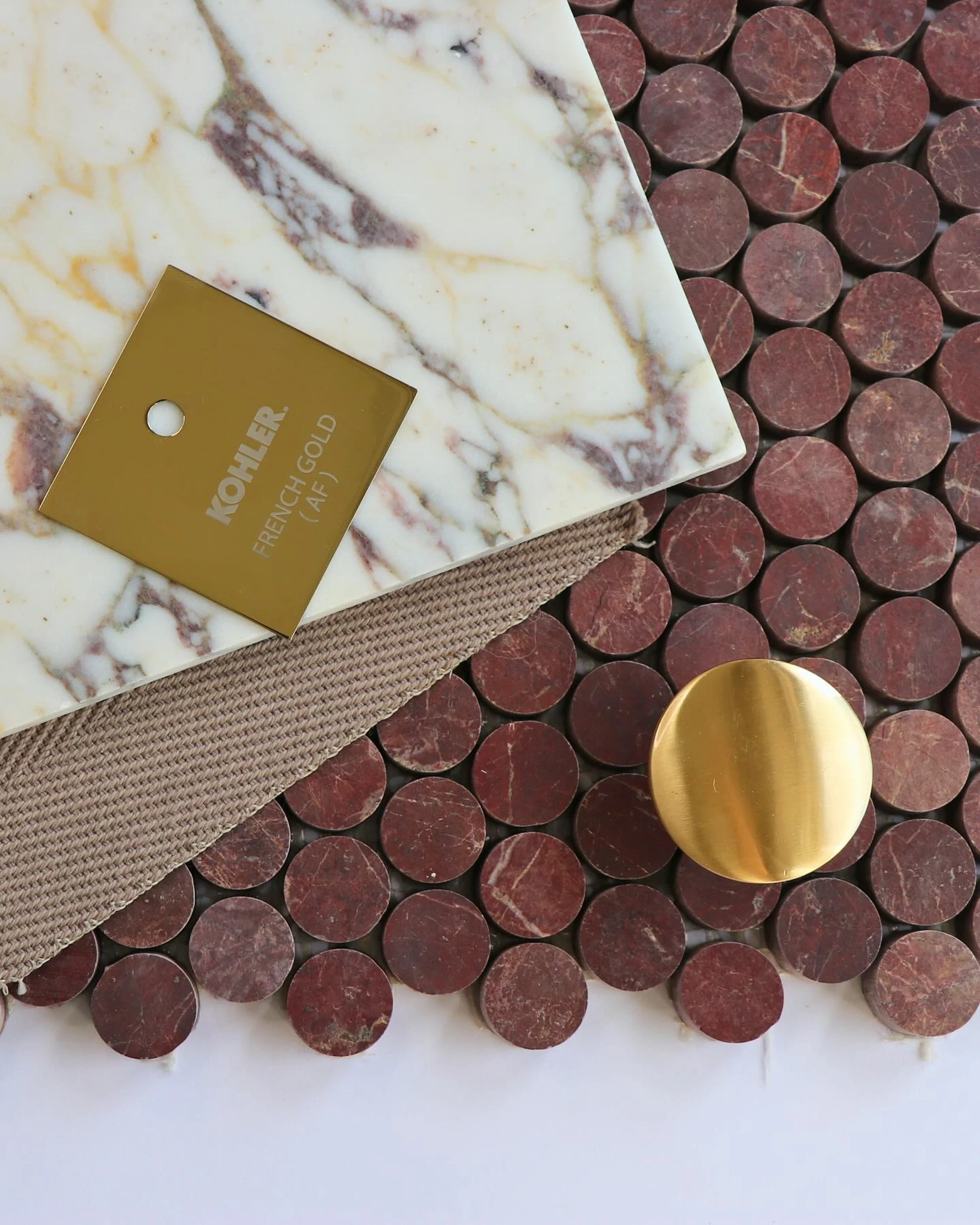Flatlay of marble, penny tile, and brass hardware for a high-end material board.