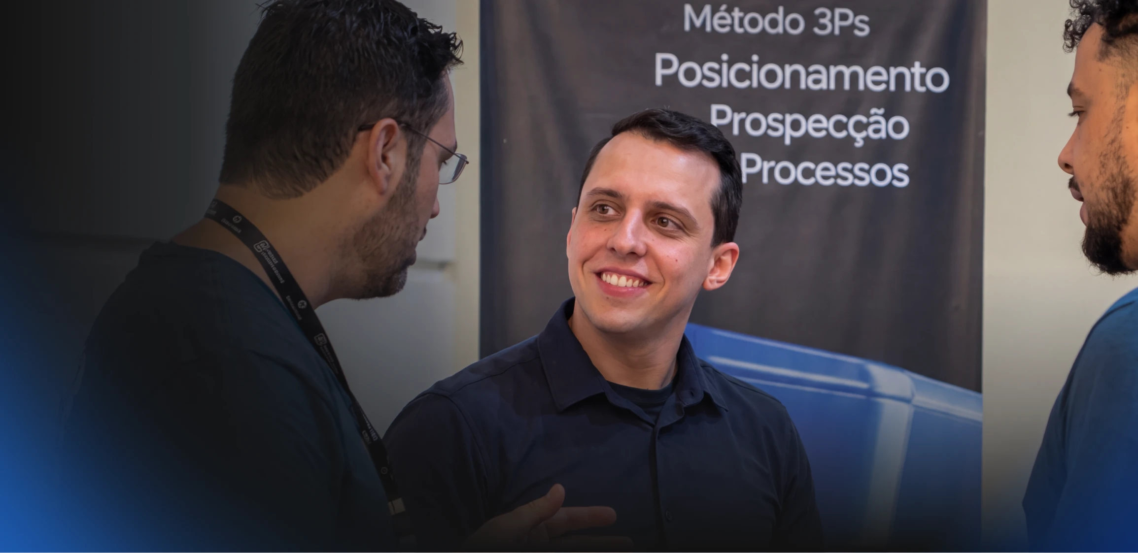 Mentor conversa com donos de agência em frente ao banner do Método 3Ps