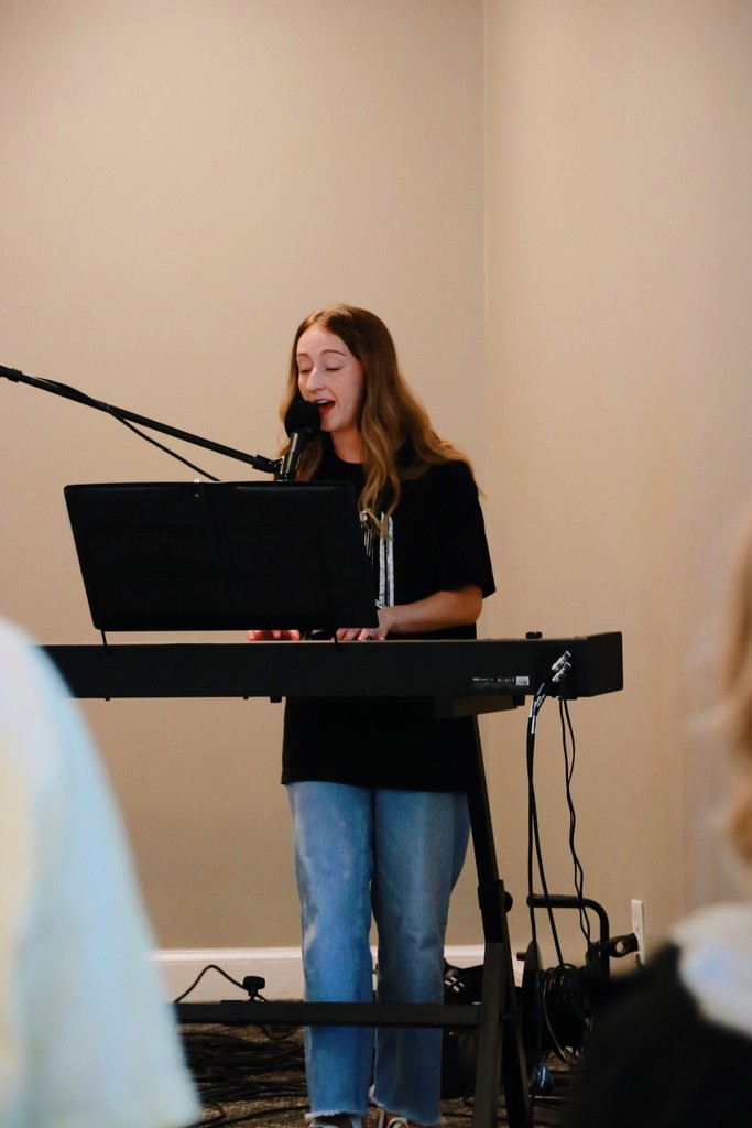 woman in gray coat singing on stage